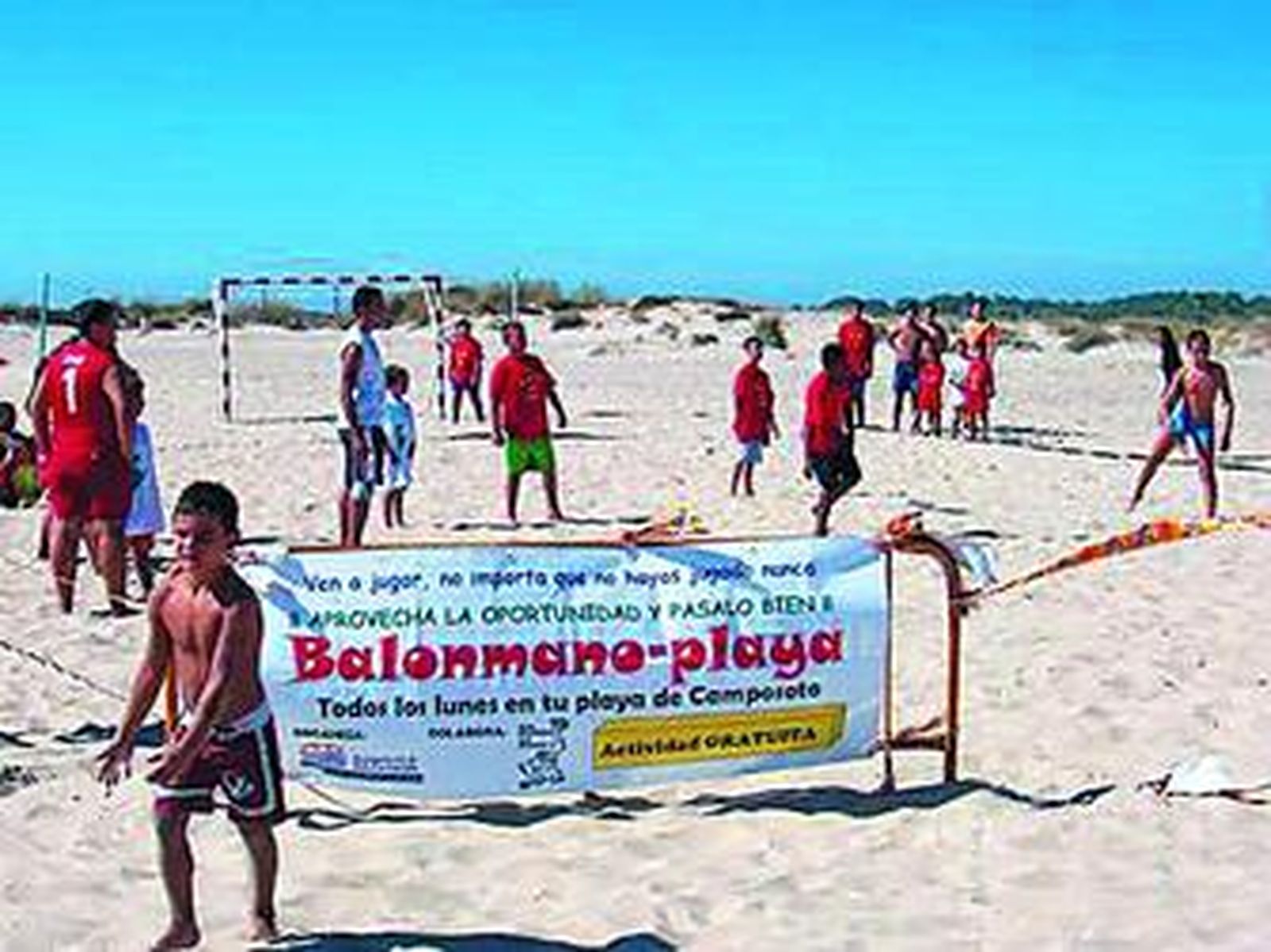 Varios jugadores practican el balonmano-playa en Camposoto bajo la atenta mirada de los monitores.