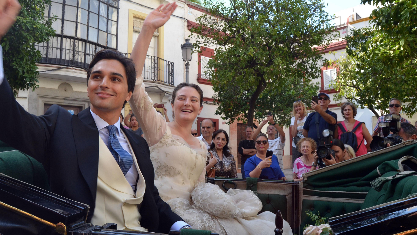 Los novios saludan montados en un coche de caballos a su salida de la iglesia de San Miguel.