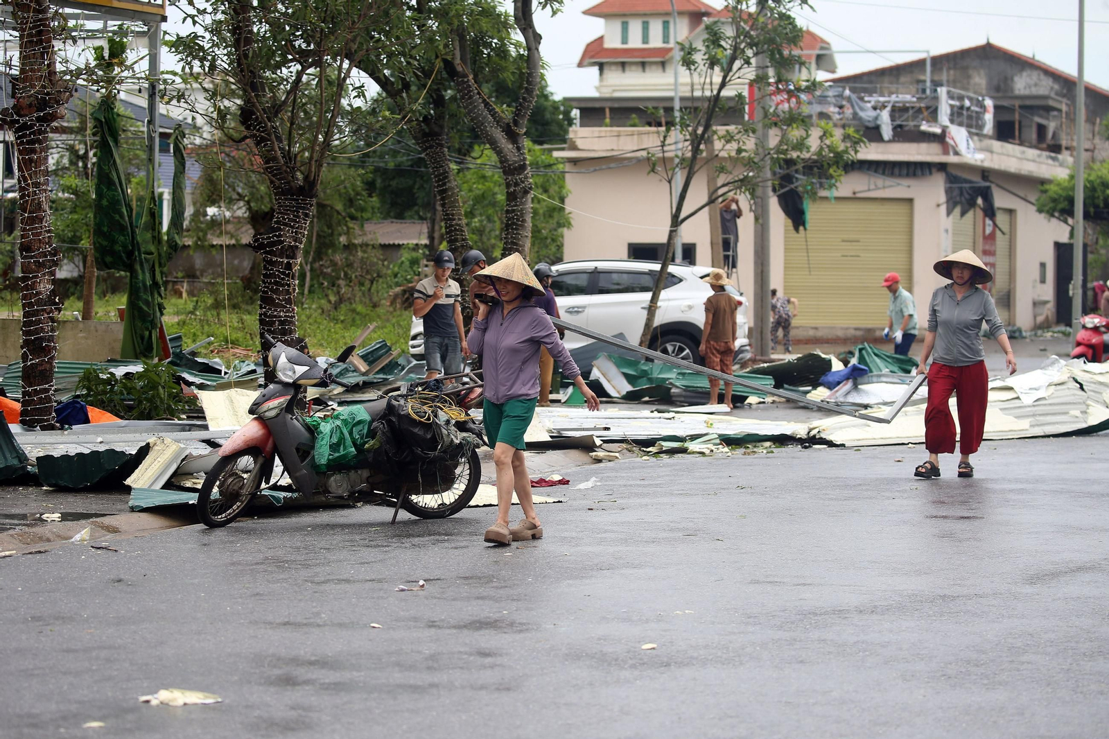 Varias personas limpian las calles de Vinh City tras el paso del tifón.