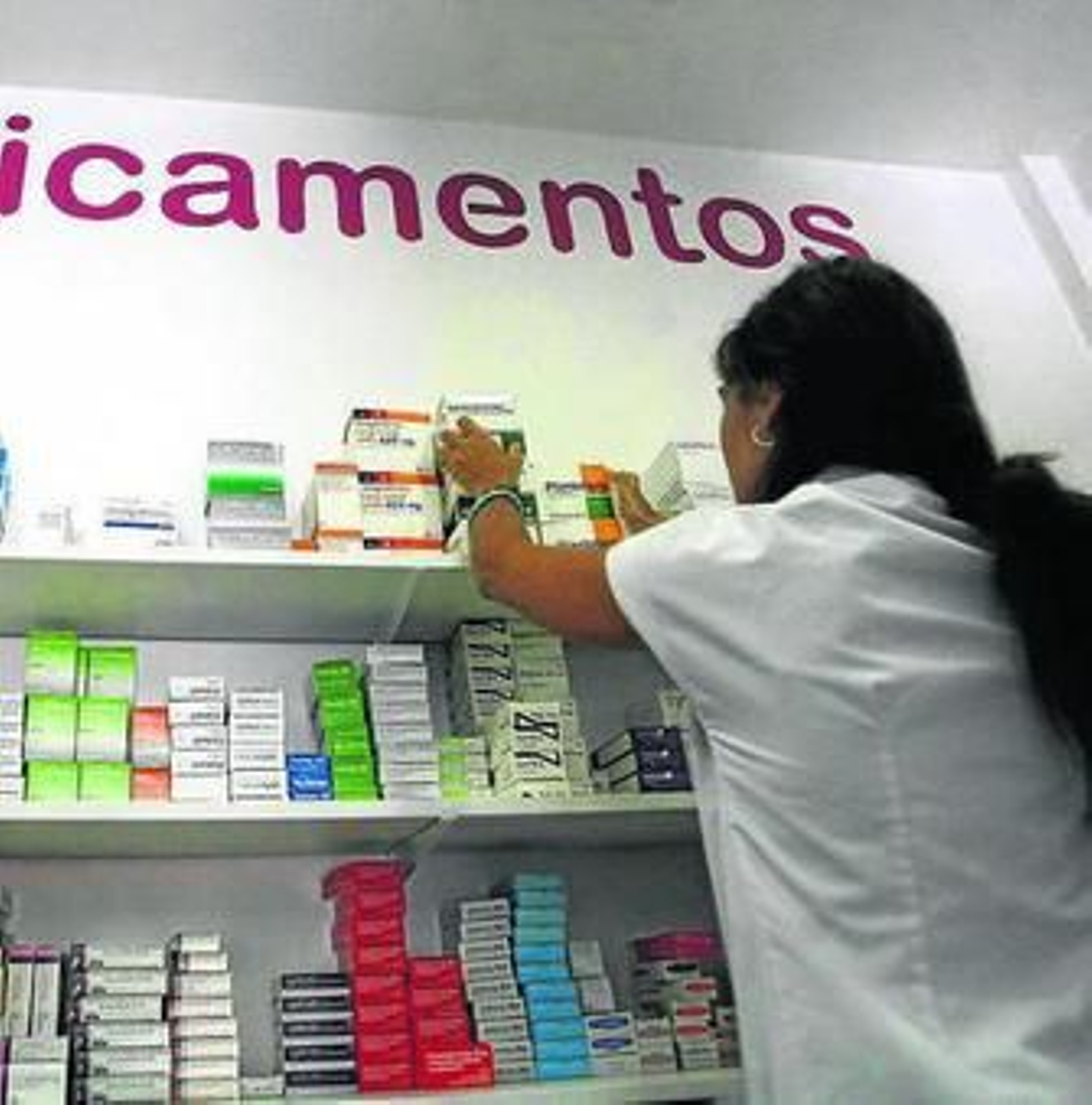 Una farmacéutica coloca medicamentos en estanterías.