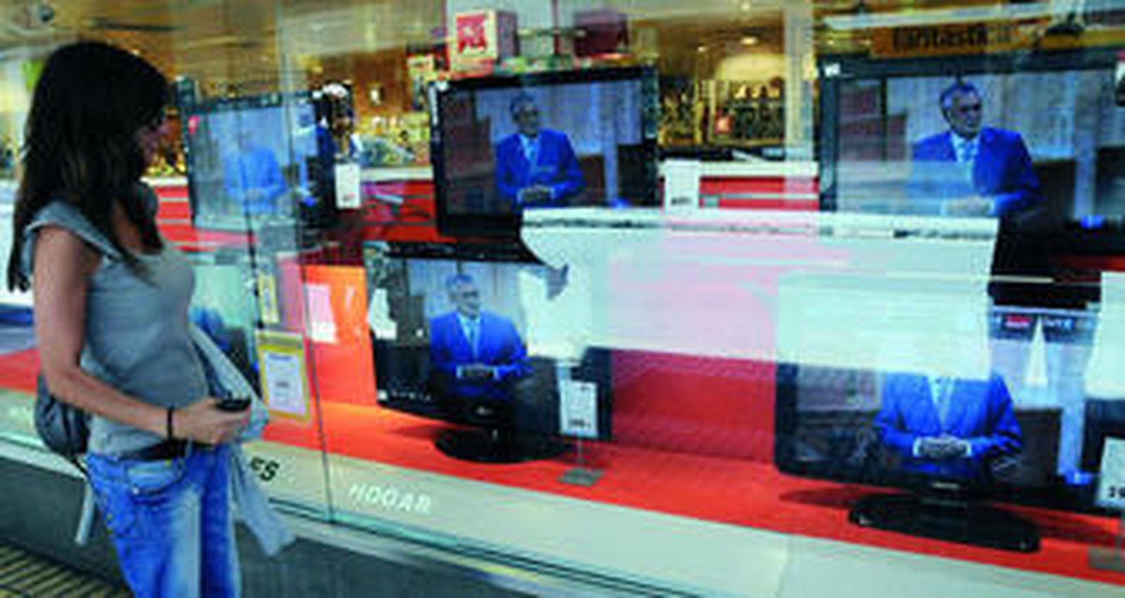 Una mujer mira ayer la imagen de Griñán repetida en varios monitores de televisión.