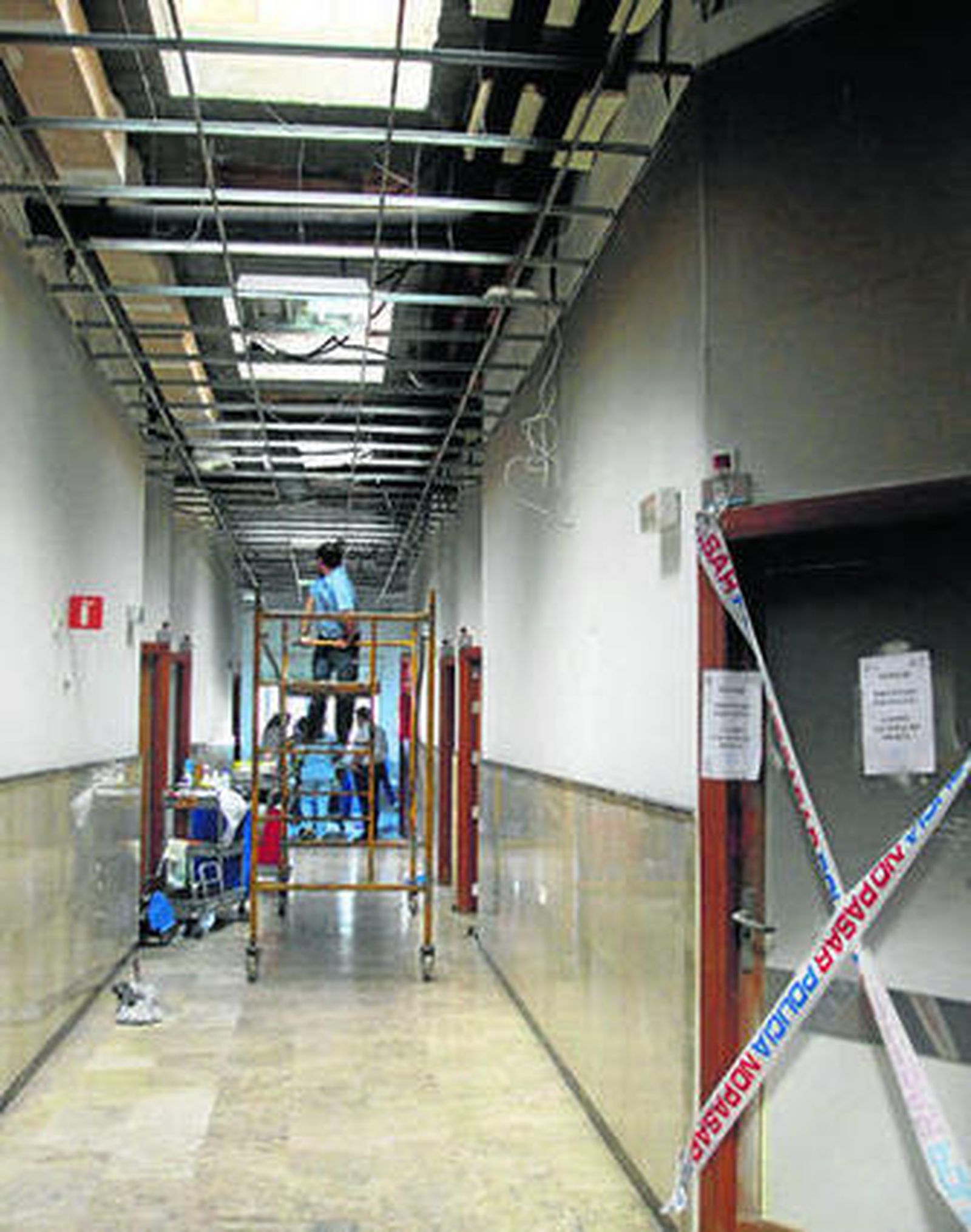 Trabajadores del centro adecentan la zona donde se produjo el incendio, precintada por la Policía.