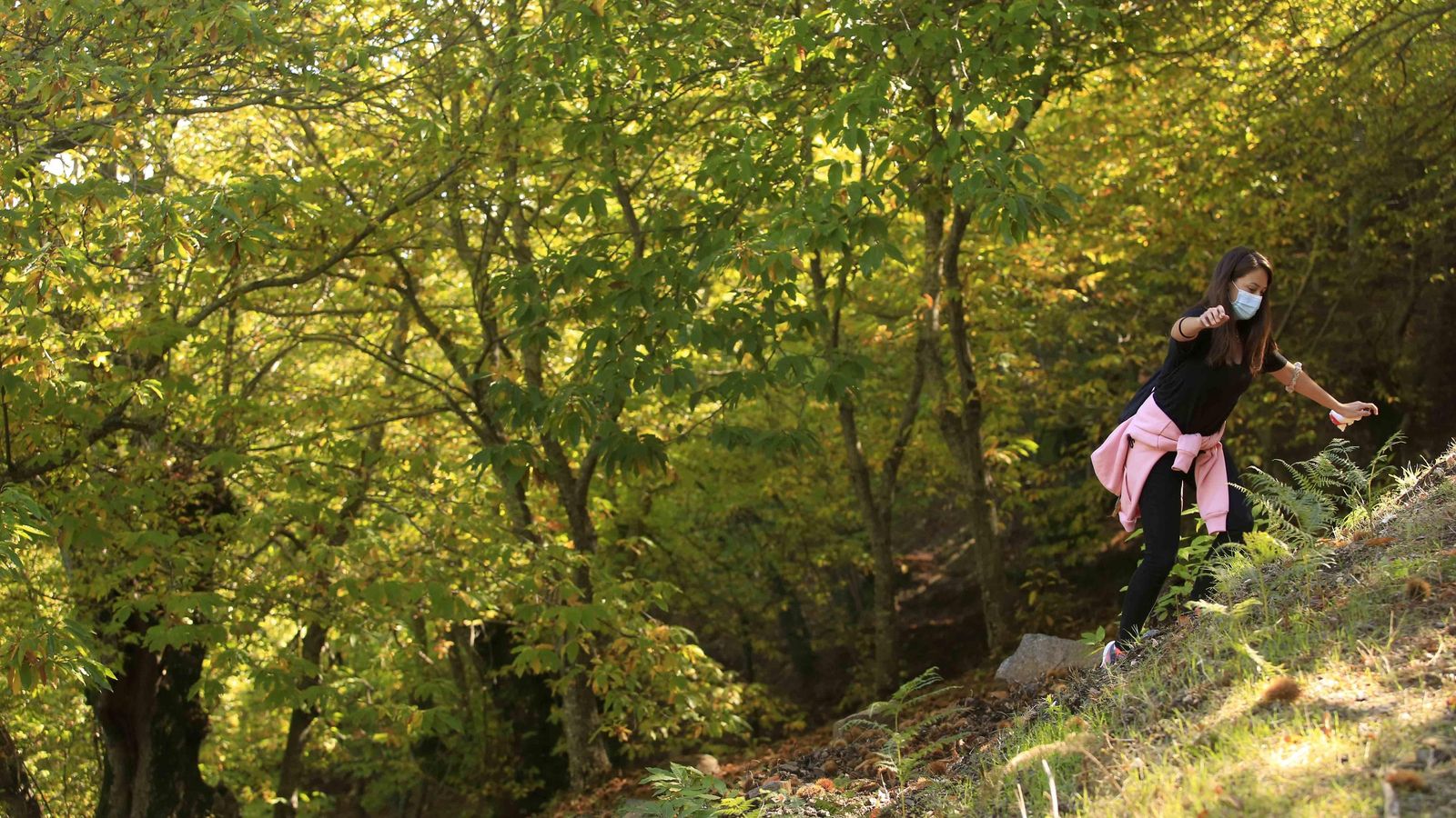 Una joven en mitad del bosque tratando de salvar la dura pendiente.