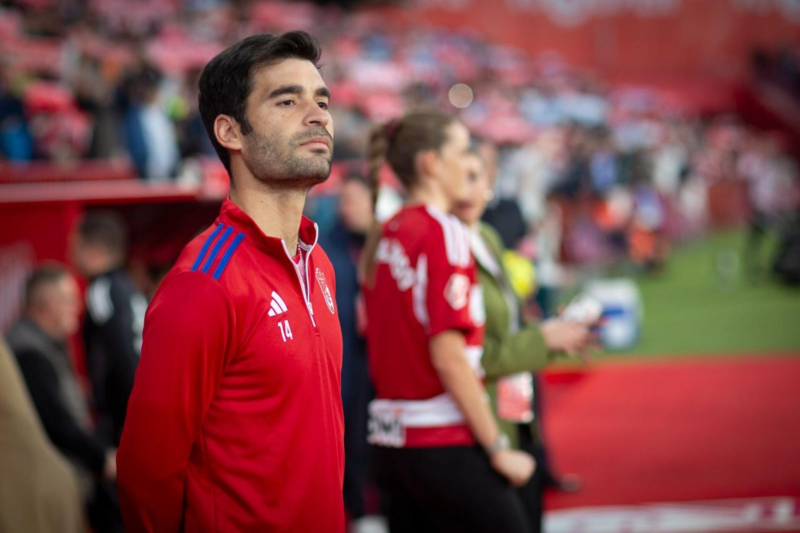 Manu Trigueros observando desde la zona de banquillos el inicio del Granada-Málaga.