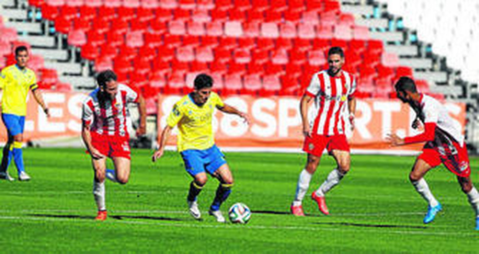 Juanma Espinosa conduce el esférico acosado por tres jugadores del Almería B.