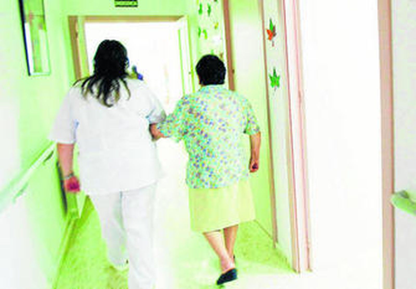 Una enfermera ayuda a una persona mayor en los pasillos de una residencia.