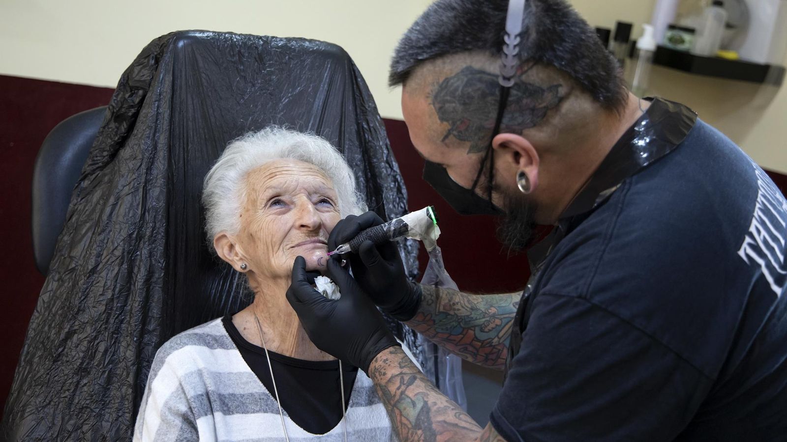 Carmen Navas, de 78 años, en las manos de Luis Solano, tatuador del estudio Redrum tattoo, en Rincón de la Victoria.