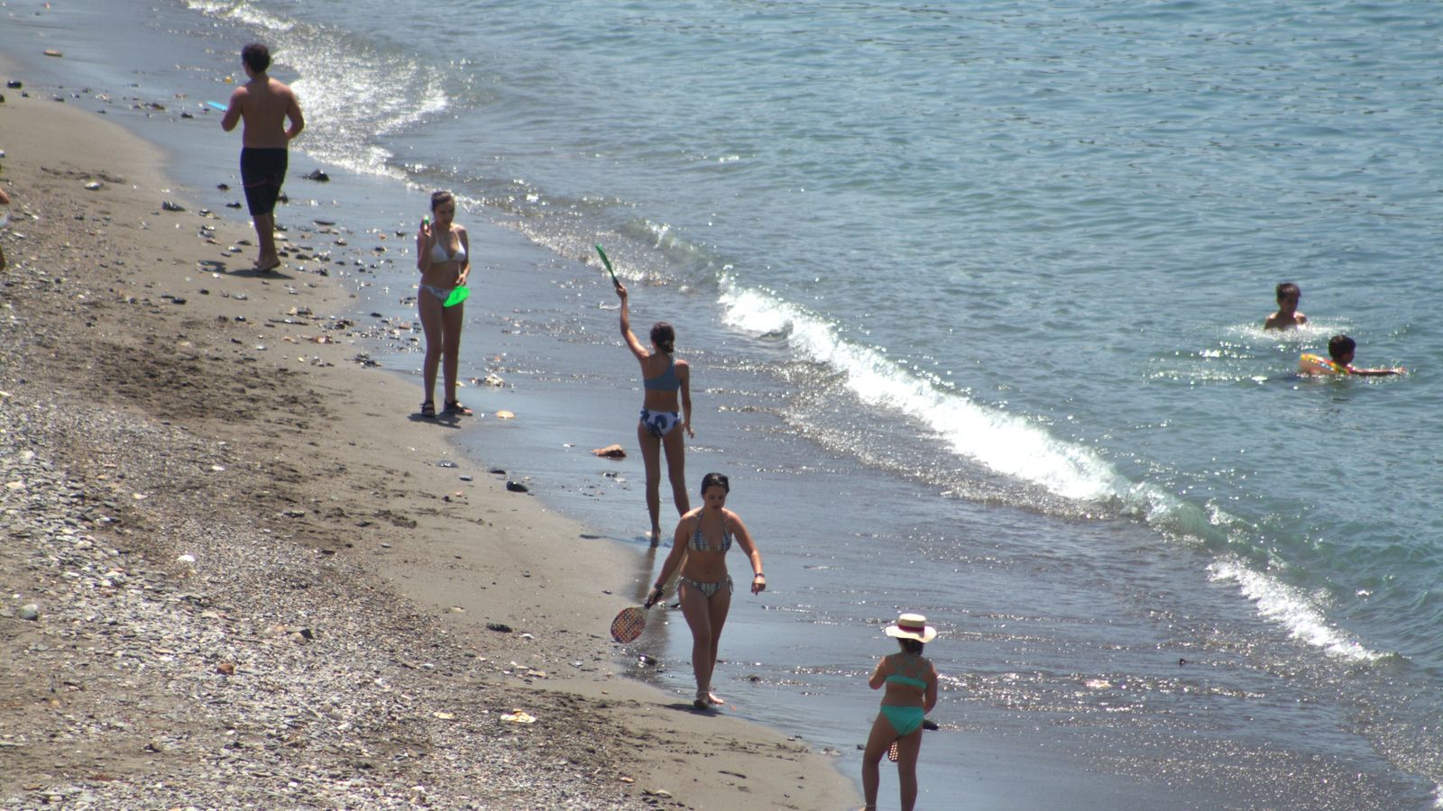 Varios bañistas disfrutan en la orilla de la playa
