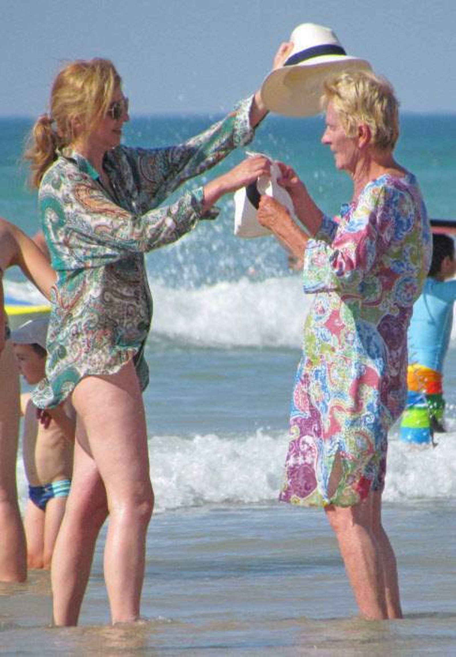 La infanta Cristina ayuda a ponerse el sombrero a su suegra, Claire, en la playa.