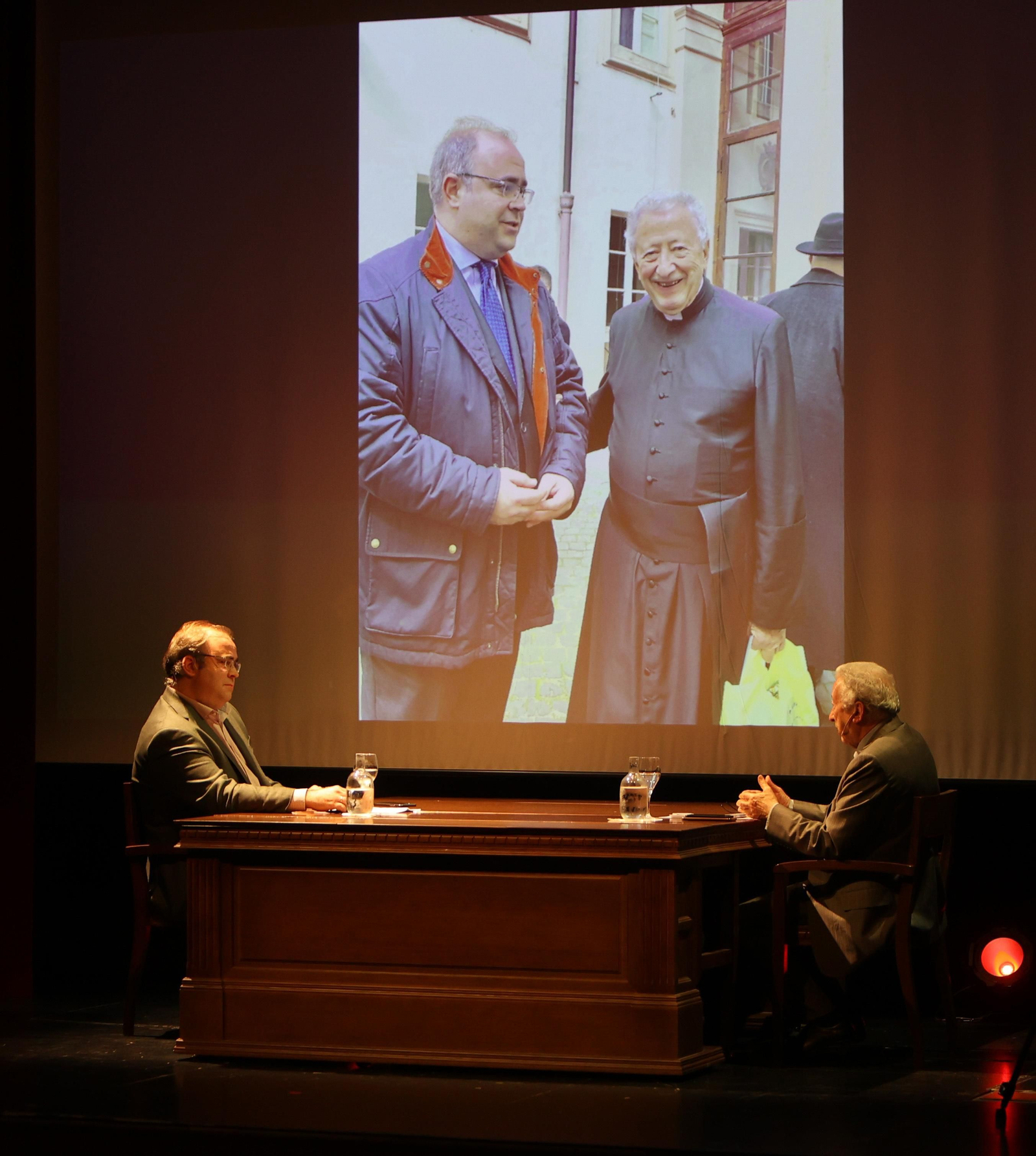 Carlos Navarro Antolín y Antonio Pelayo conversan. Al fondo, una foto de sus encuentros en Roma.