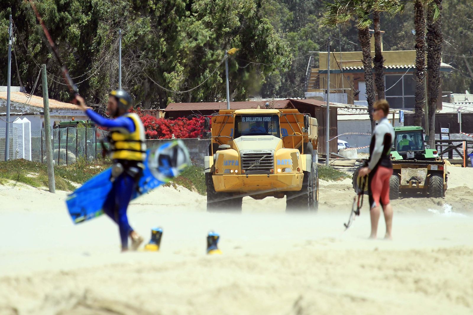 Aficionados al 'kite' practican esta modalidad deportiva en la playa de Palmones ante la presencia de máquinas que aportan arena al litoral.