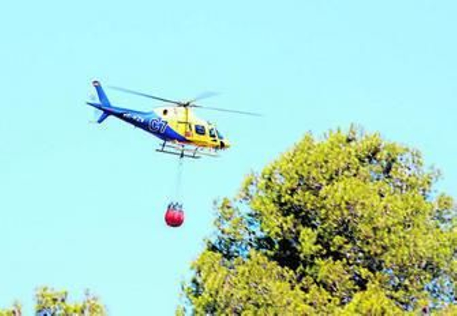Un helicóptero refresca, ayer, la zona afectada por el fuego.