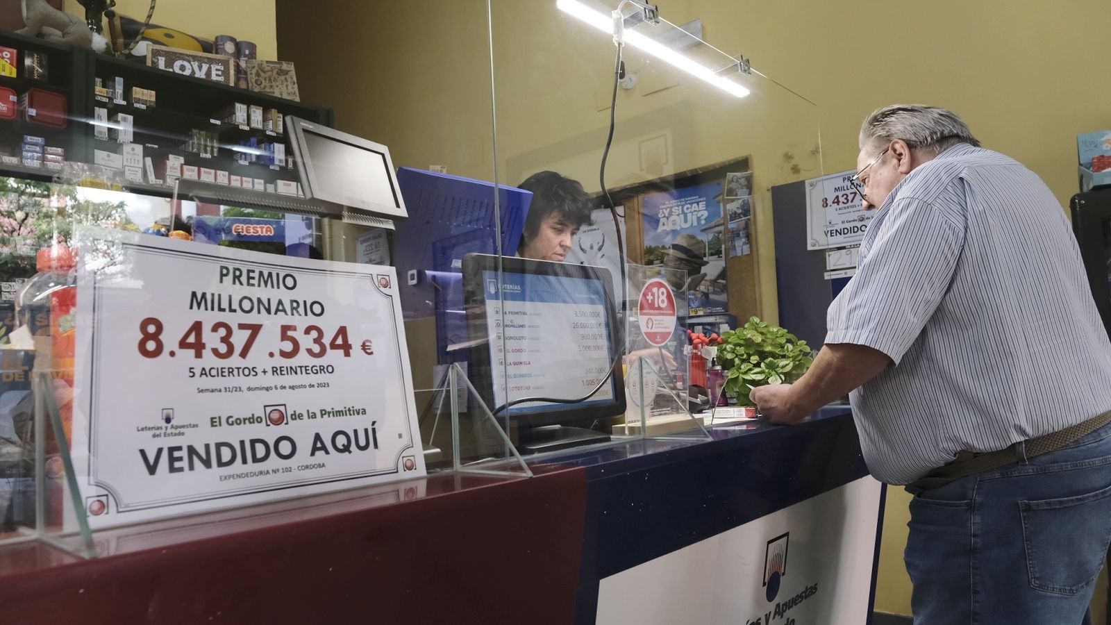 África Úbeda atiende a un cliente junto al cartel del primer premio del Gordo de la Primitiva.