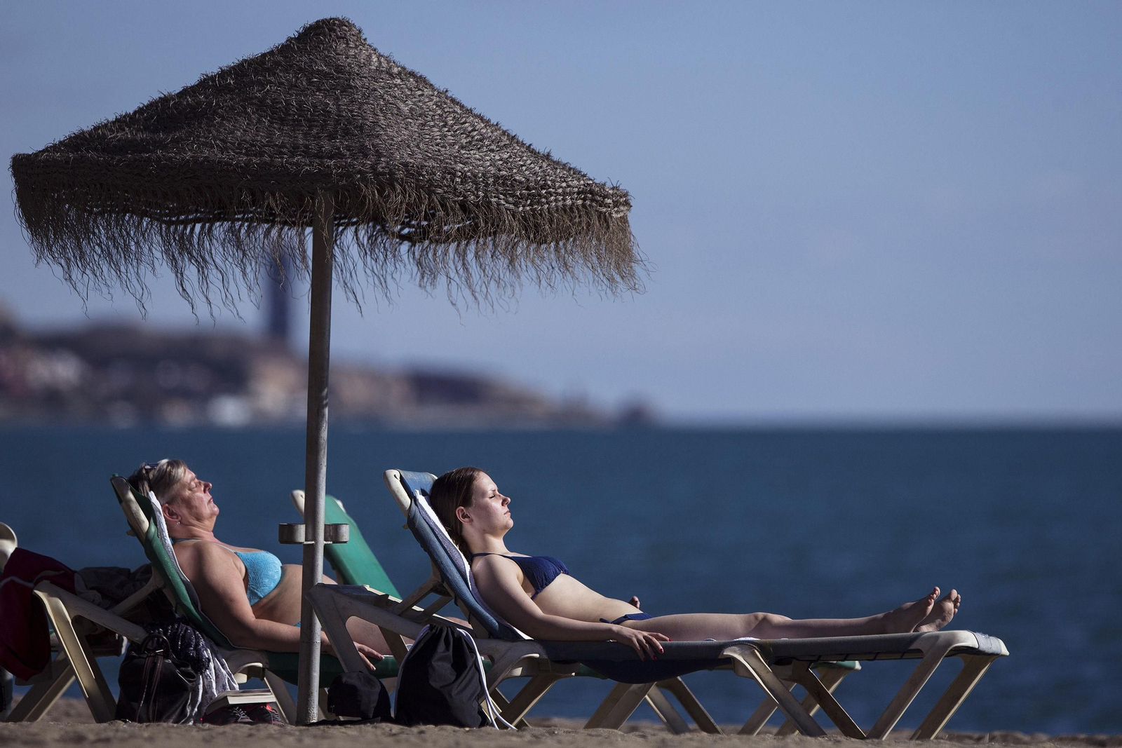 Dos mujeres toman el sol en una playa de Málaga.