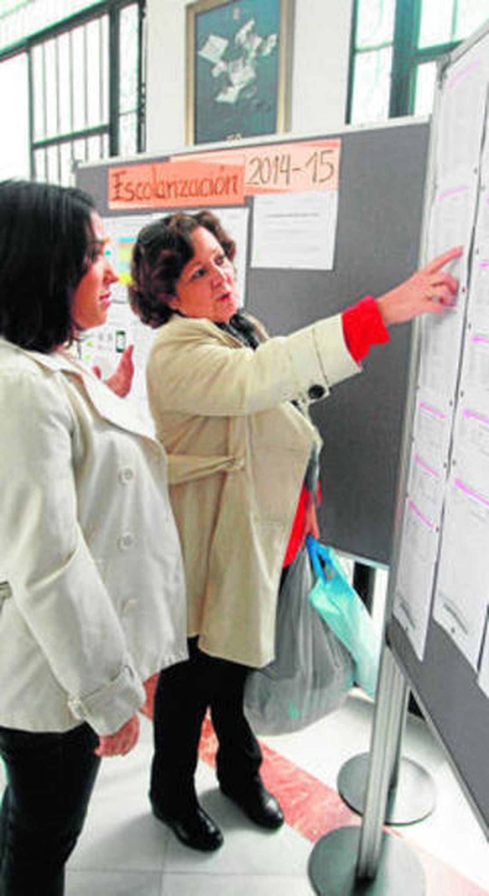 Familiares de alumnos comprueban las listas en la pasada escolarización.