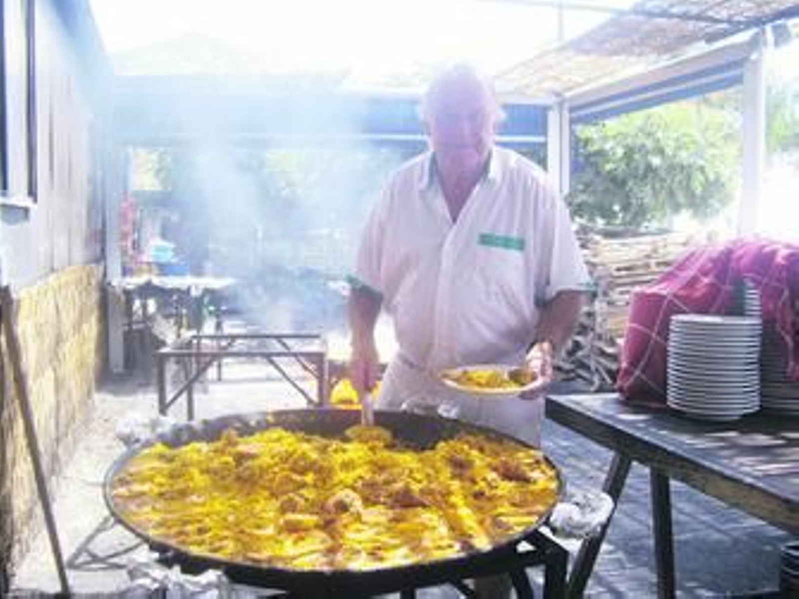 Francisco Ortega sirve un plato de paella en su chiringuito, en una imagen que se ha convertido en toda una estampa tradicional en la zona.