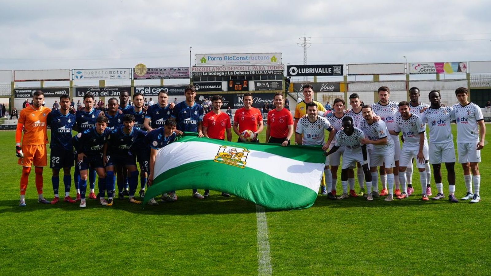 Jugadores de Pozoblanco, Balona y el trío arbitral posan con la bandera de Andalucía antes del inicio del encuentro