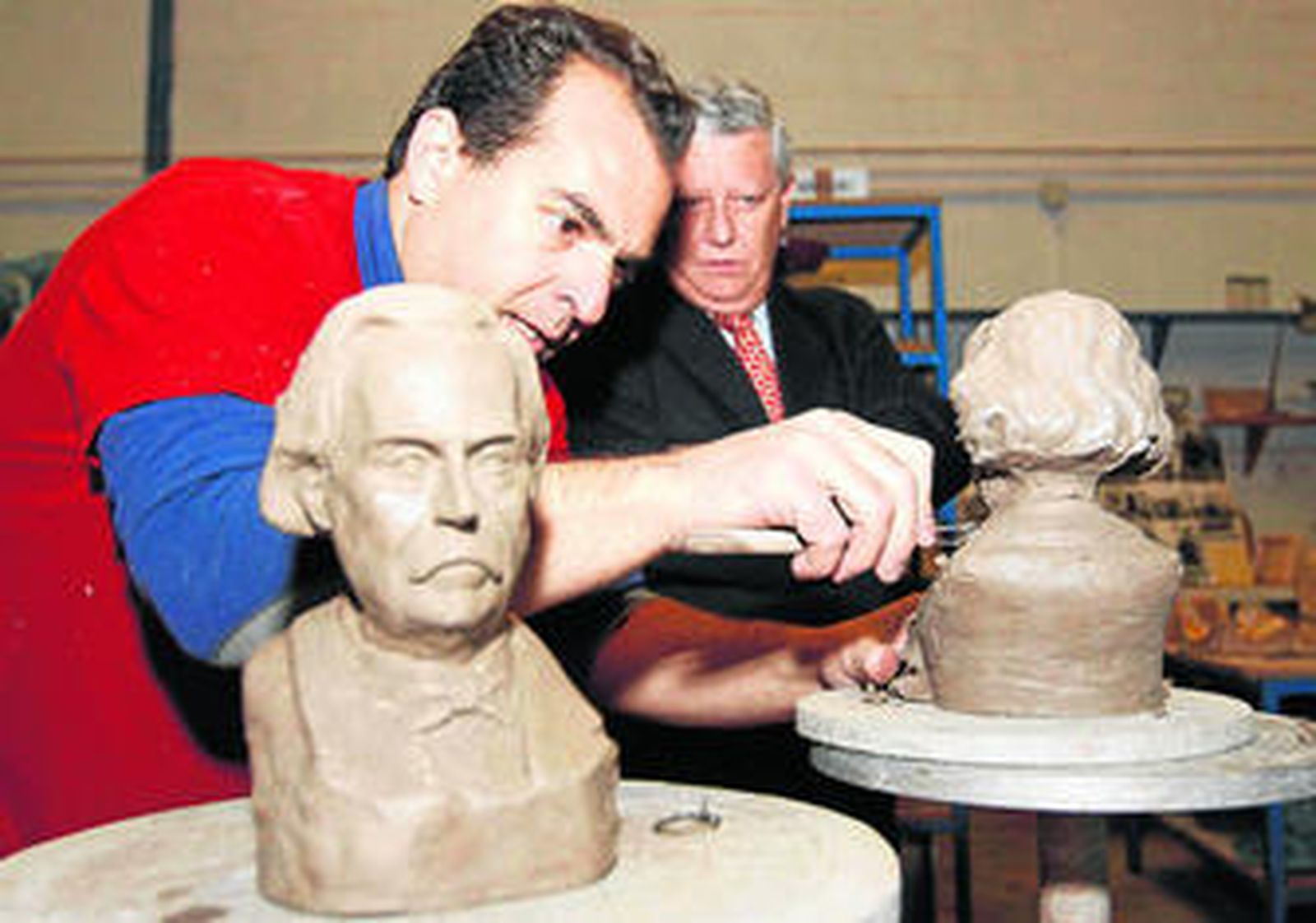 El autor de los bustos modela uno de ellos ante la mirada del alcalde.
