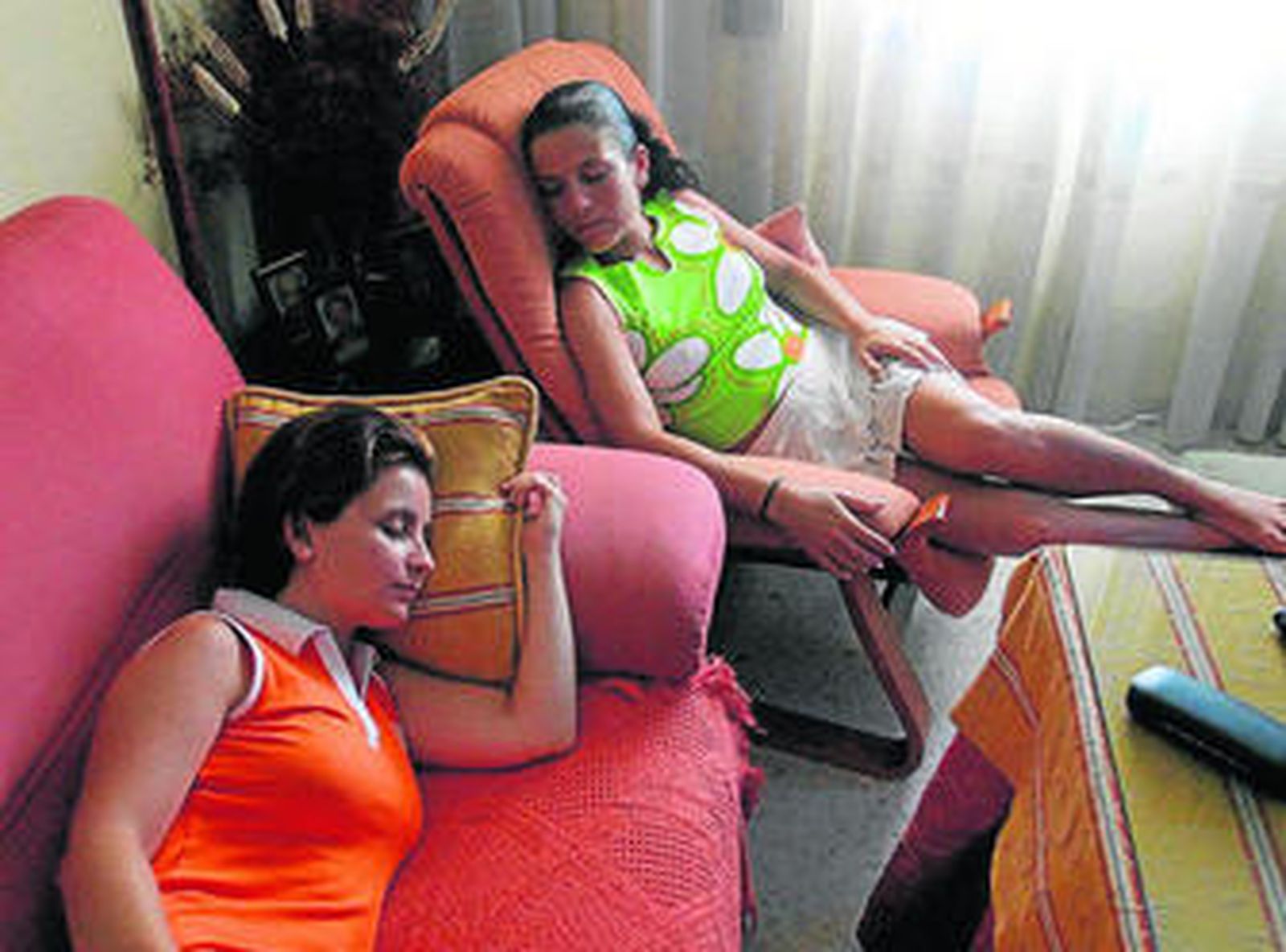 Dos jóvenes duermen la siesta en el salón de su casa.