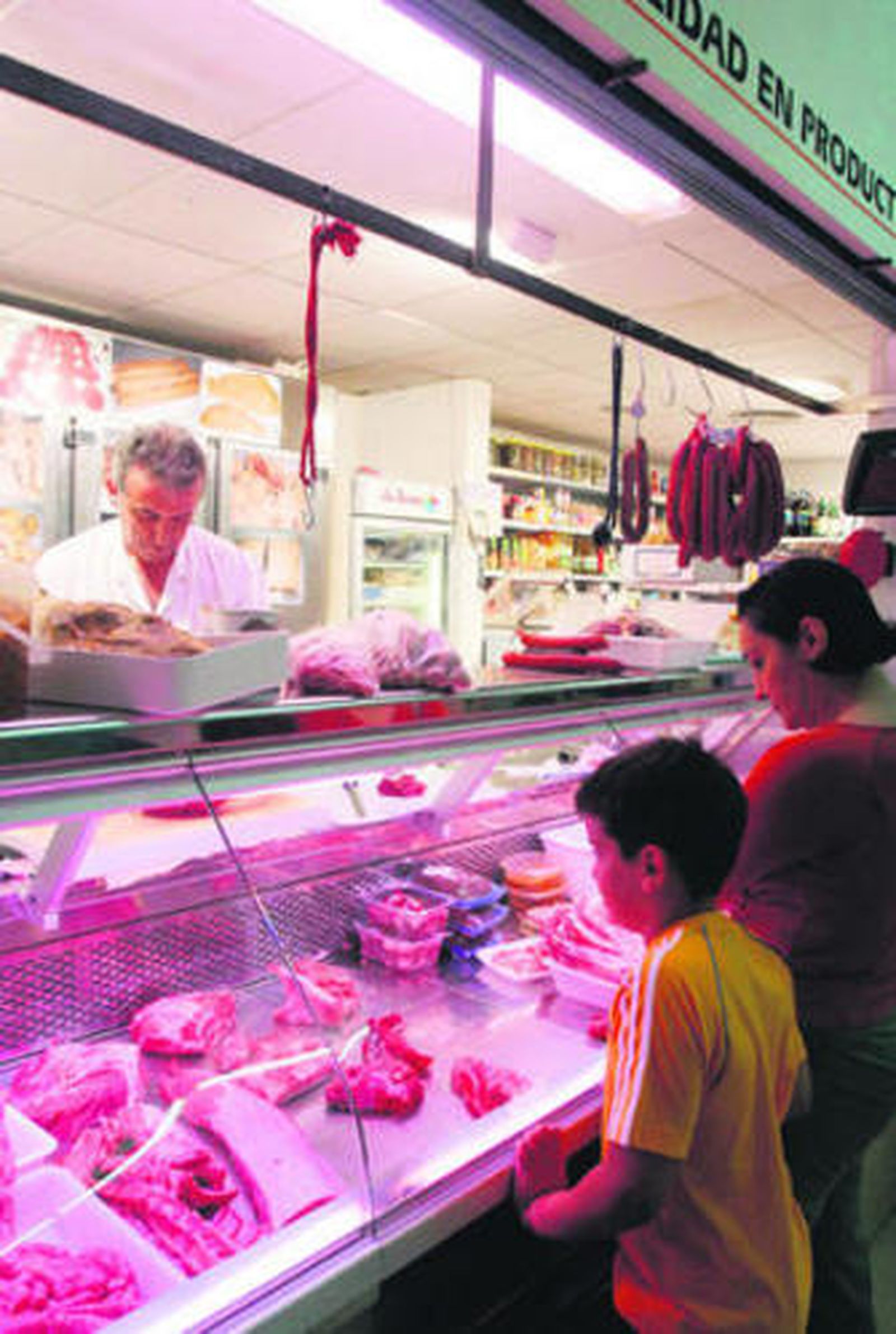 Una familia compra carne en un mercado municipal.