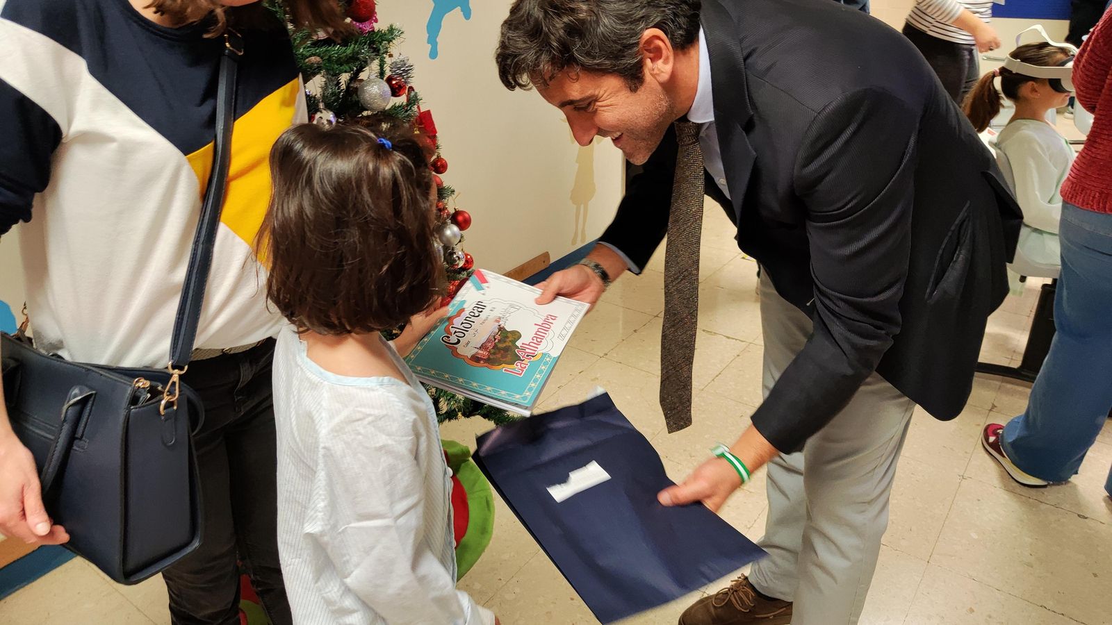 El jefe de Visita Pública del Patronato de la Alhambra y Generalife, Gonzalo Mochón, entrega un regalo a una de las asistentes