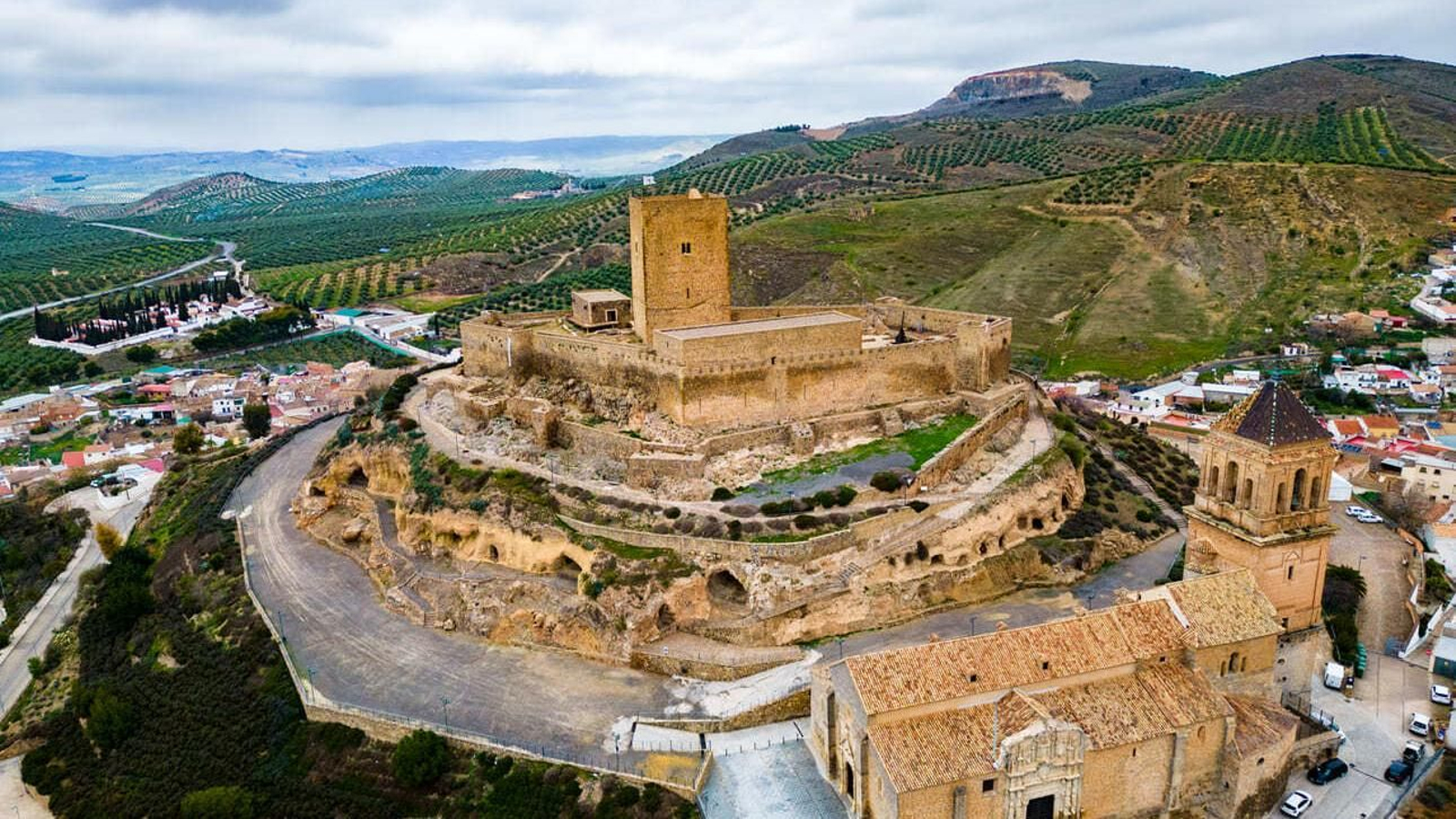 El Castillo de Alcaudete y la Iglesia de Santa María la Mayor en una panorámica con la Sierra Sur de Jaén al fondo.