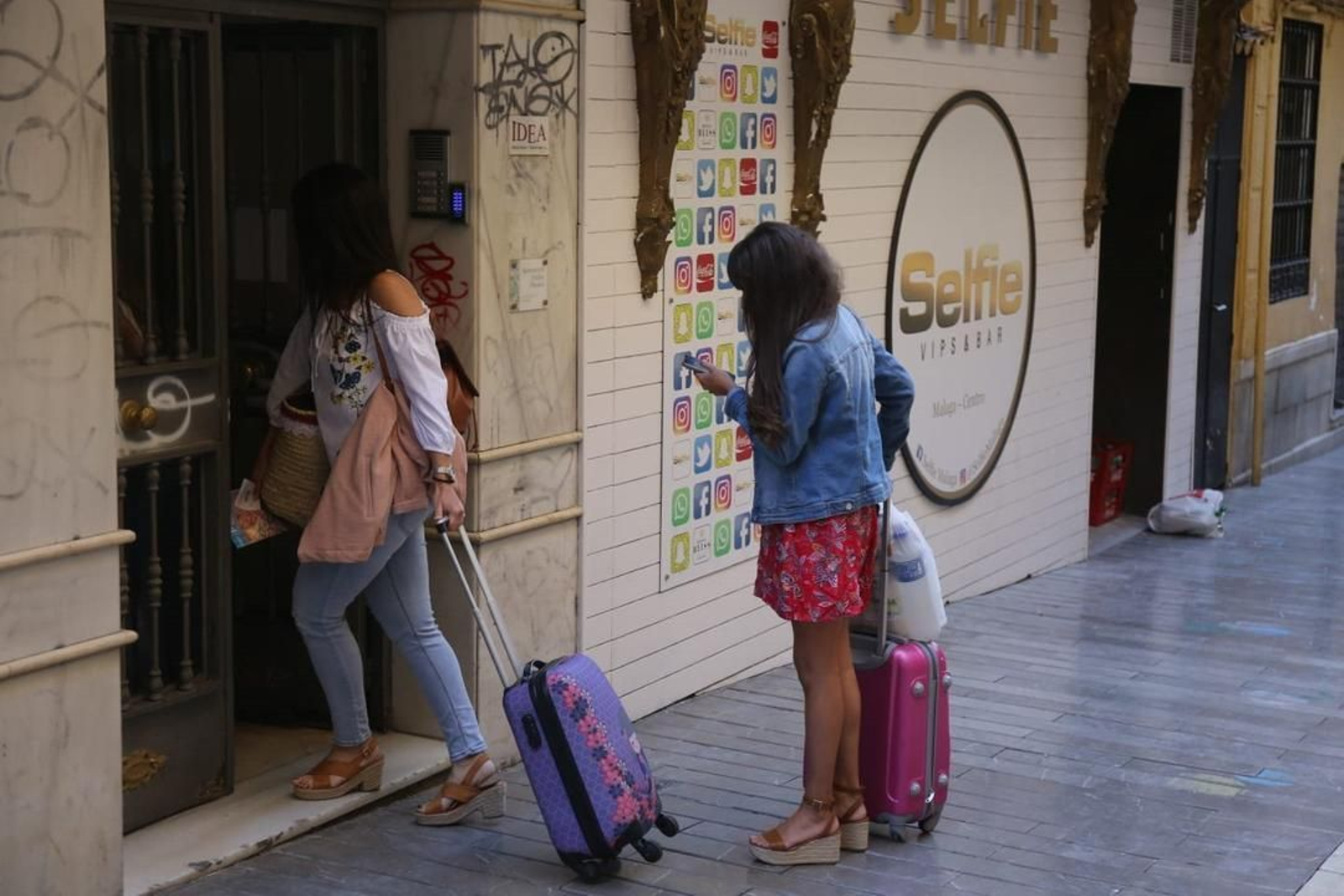 Dos jóvenes entran a un edificio con viviendas turísticas.