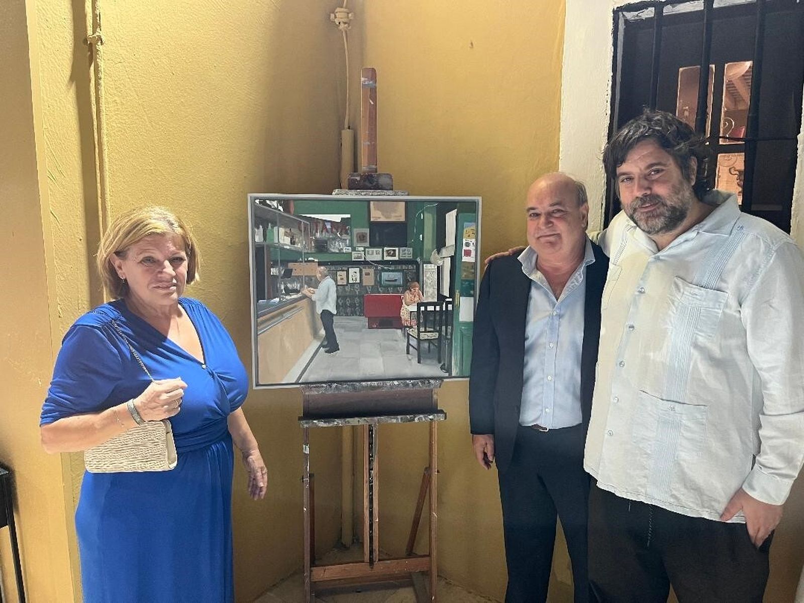 Ana García  y Pelayo García Borbolla, con el pintor Pepe Baena, ante una pintura que representa a los homenajeados en su histórico restaurante.