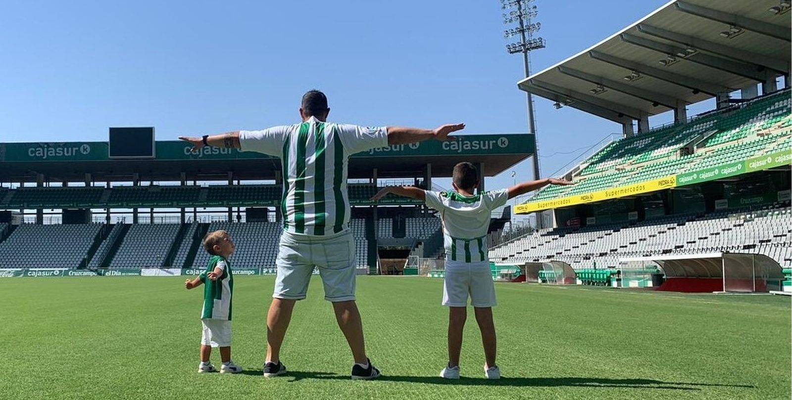 Un abonado del Córdoba CF y sus dos hijos se fotografían sobre el césped de El Arcángel.