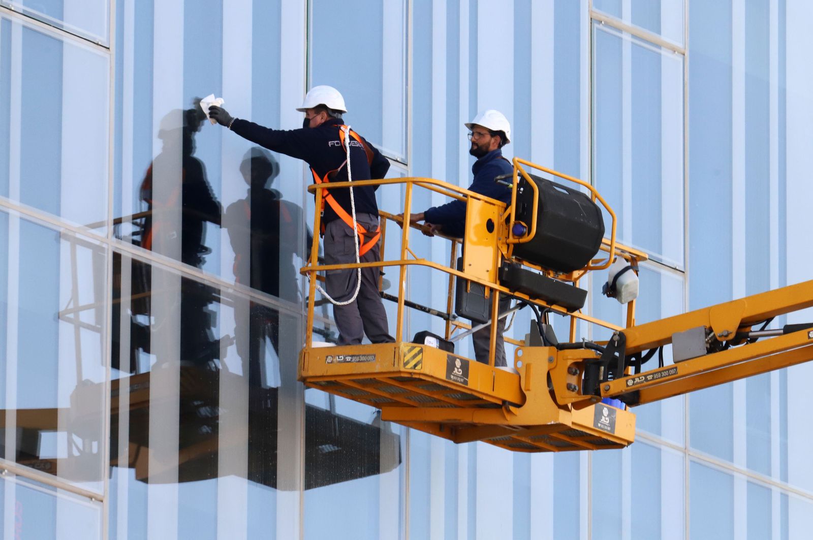 Dos operarios trabajan en la fachada de un edificio en Huelva.