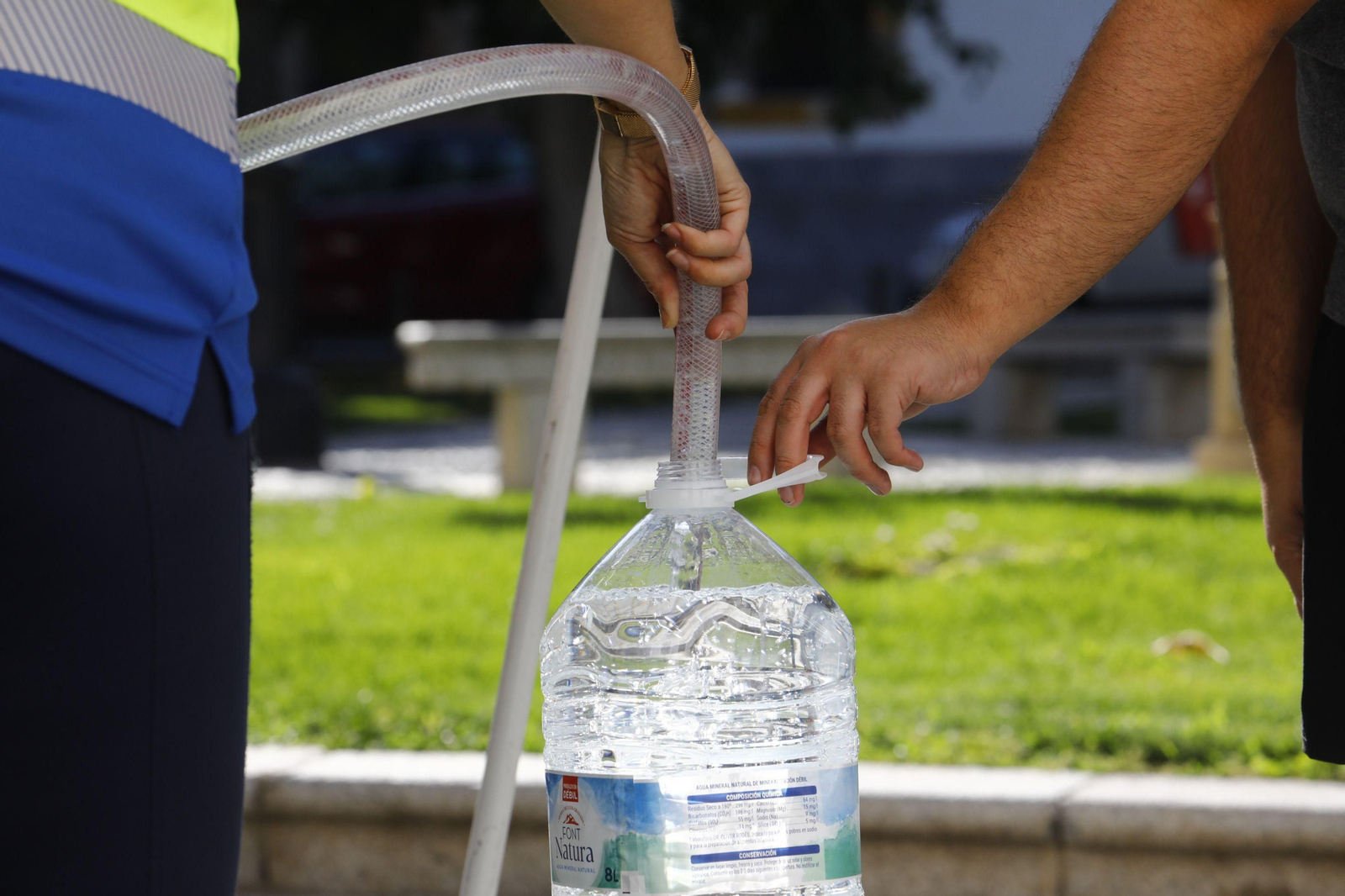 Un vecino llena una botella de agua de un camión cisterna.