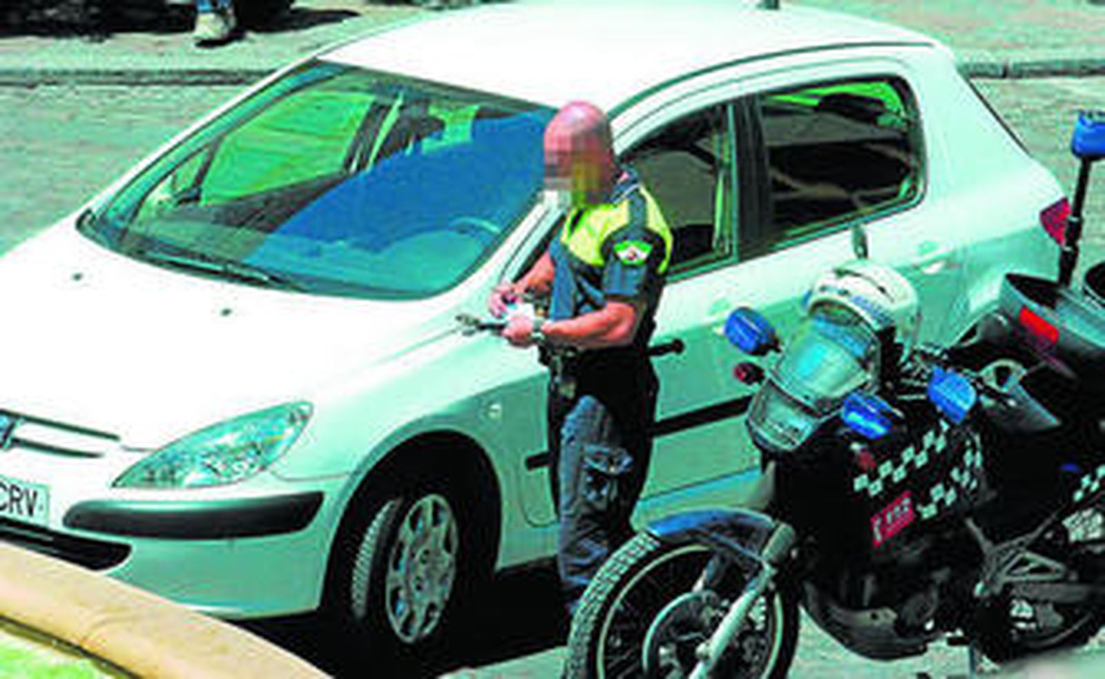 Un agente de la Policía Local pone una multa a un vehículo.