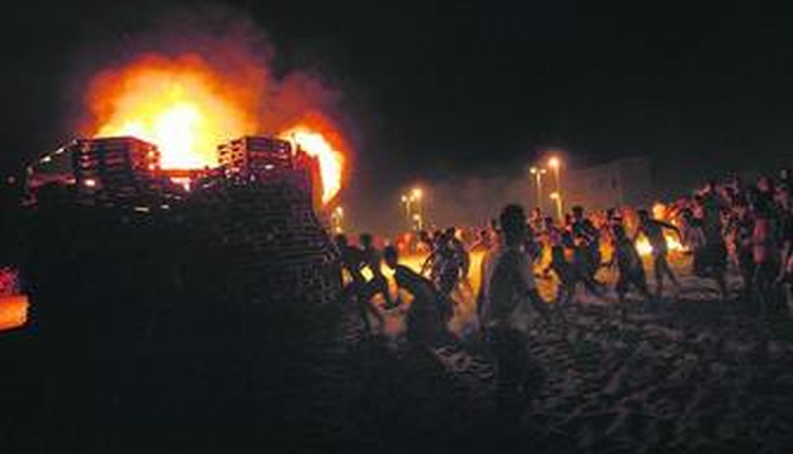 Numerosas personas se apilan alrededor de uno de los fuegos en la playa linense de La Atunara.