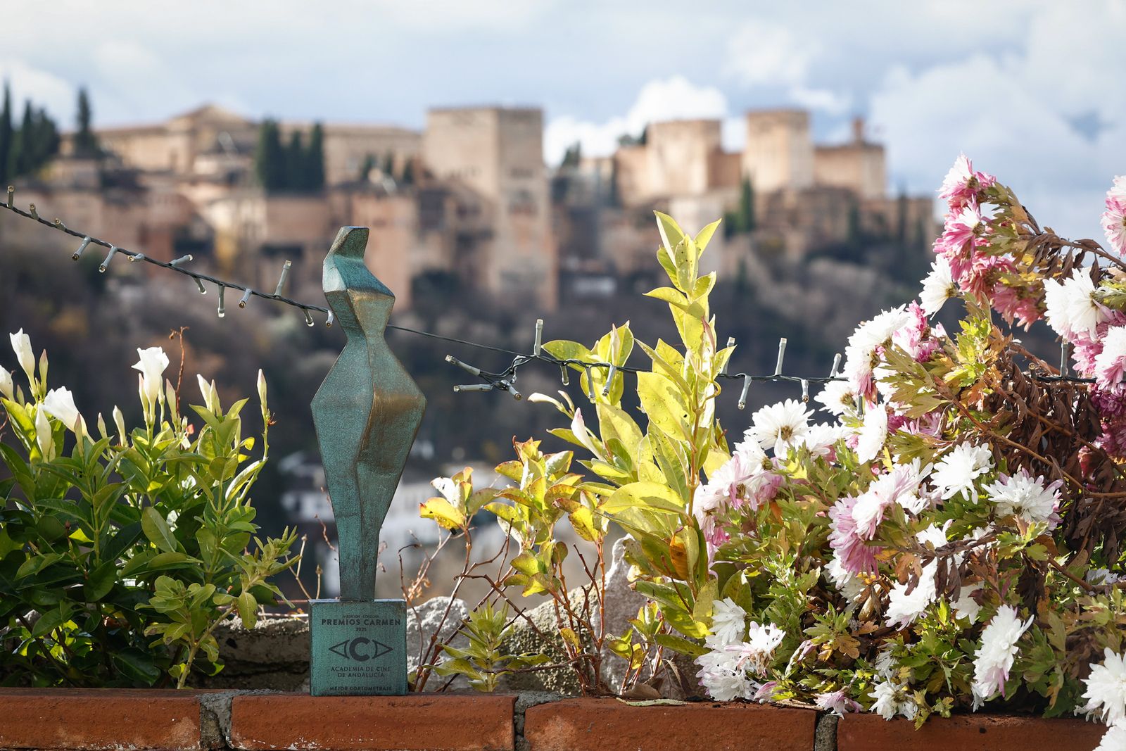 La estatuilla de los Premios Caramen con la Alhambra de fondo.
