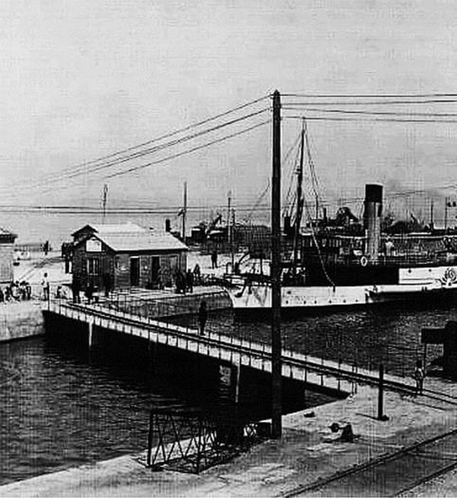 Puente de la Desembocadura o de las vagonetas. Obsérvense los raíles del ferrocarril de vía estrecha  y uno de los notables vapores con propulsión a ruedas de paletas, que ya eran una rareza en esa época.