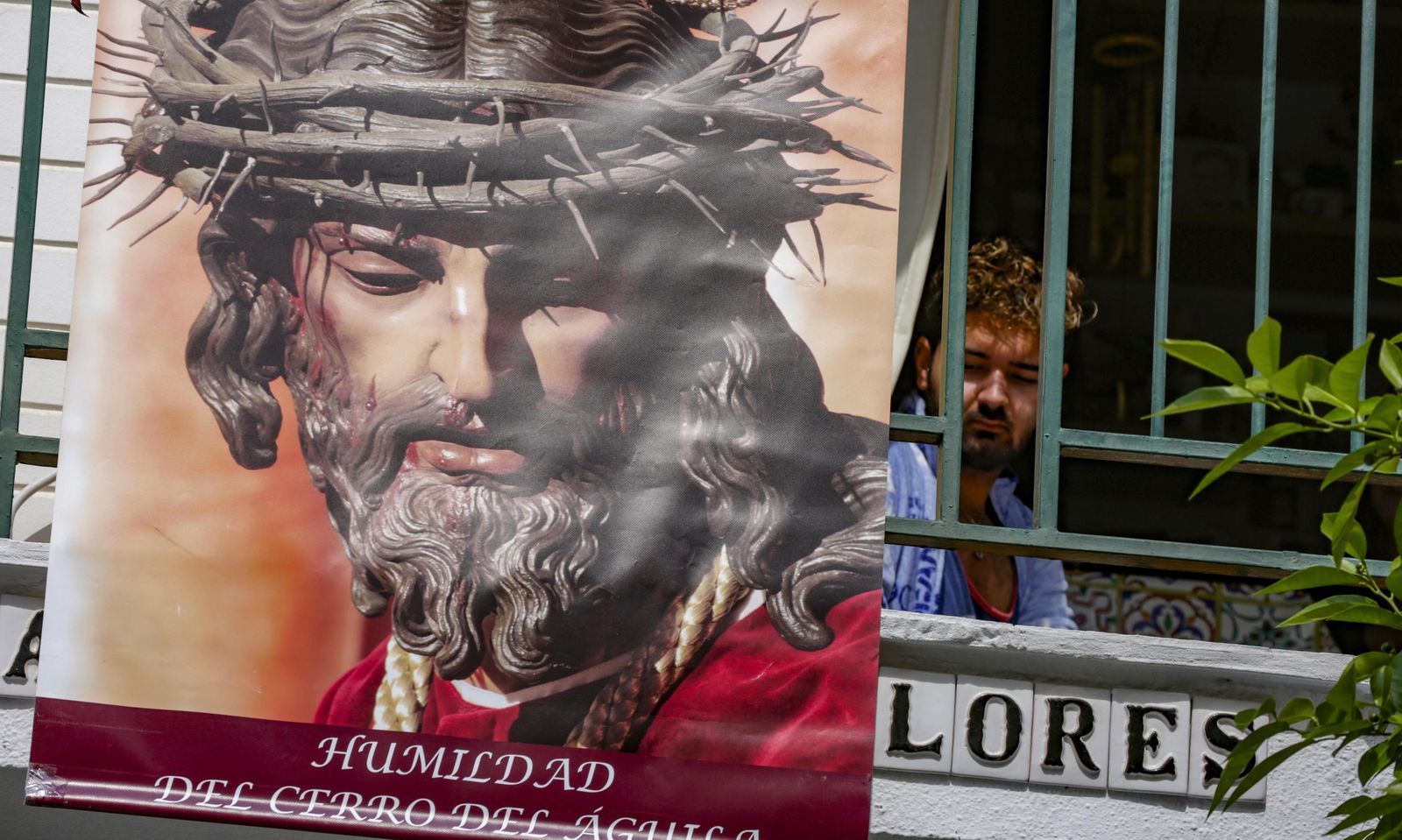 Un vecino mira hacia el  vacío del Martes  Santo desde un balcón del barrio del Cerro  adornado con el  Señor de la  Humildad/ Juan Carlos Muñoz.