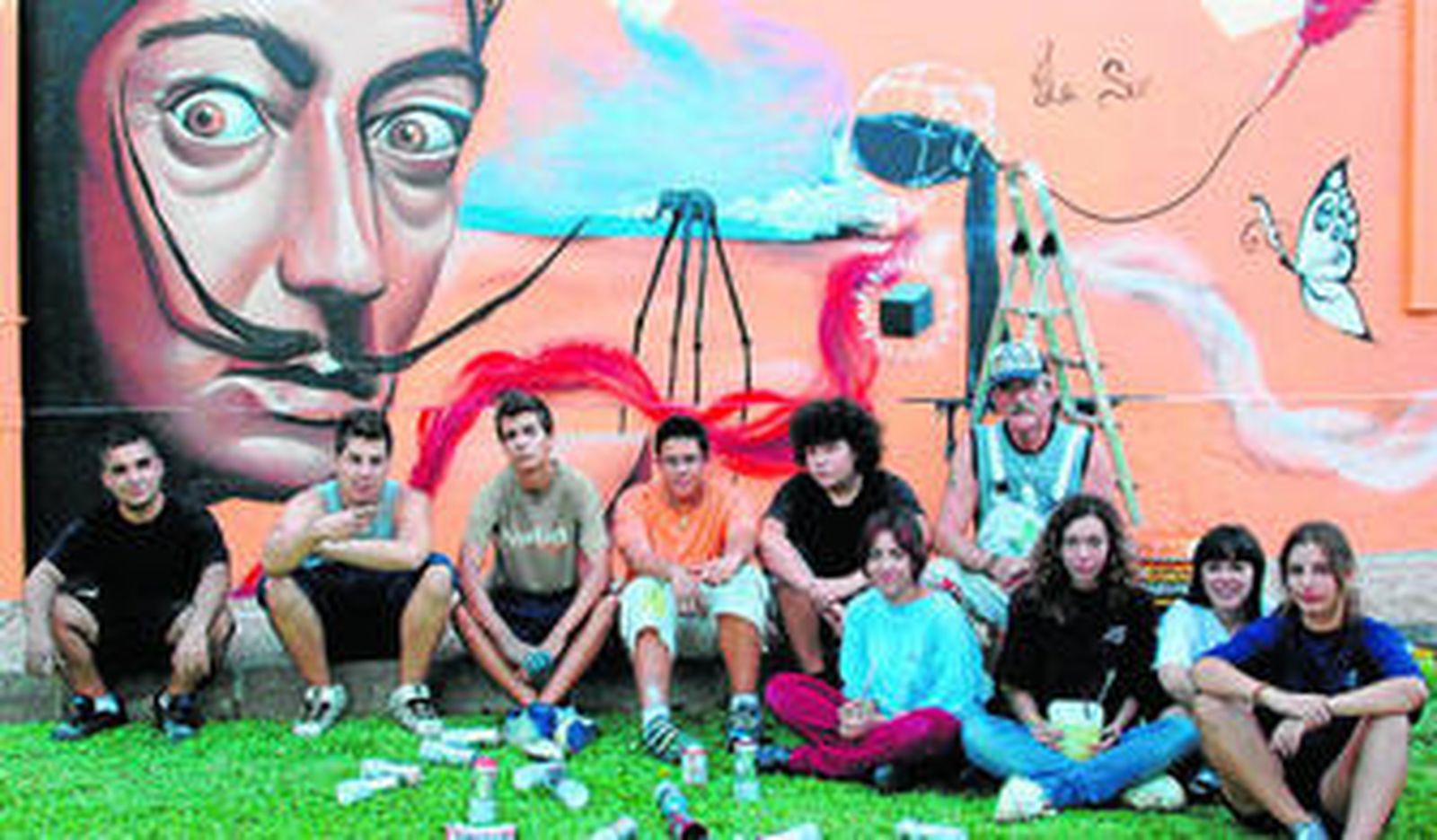 Varios miembros de 'Hormiga azul' delante de un grafiti en el que aparece el pintor Salvador Dalí.