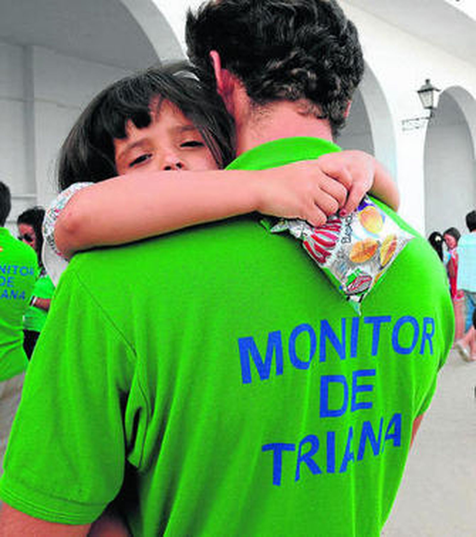 Un niño en brazos de uno de los monitores de las colonias.