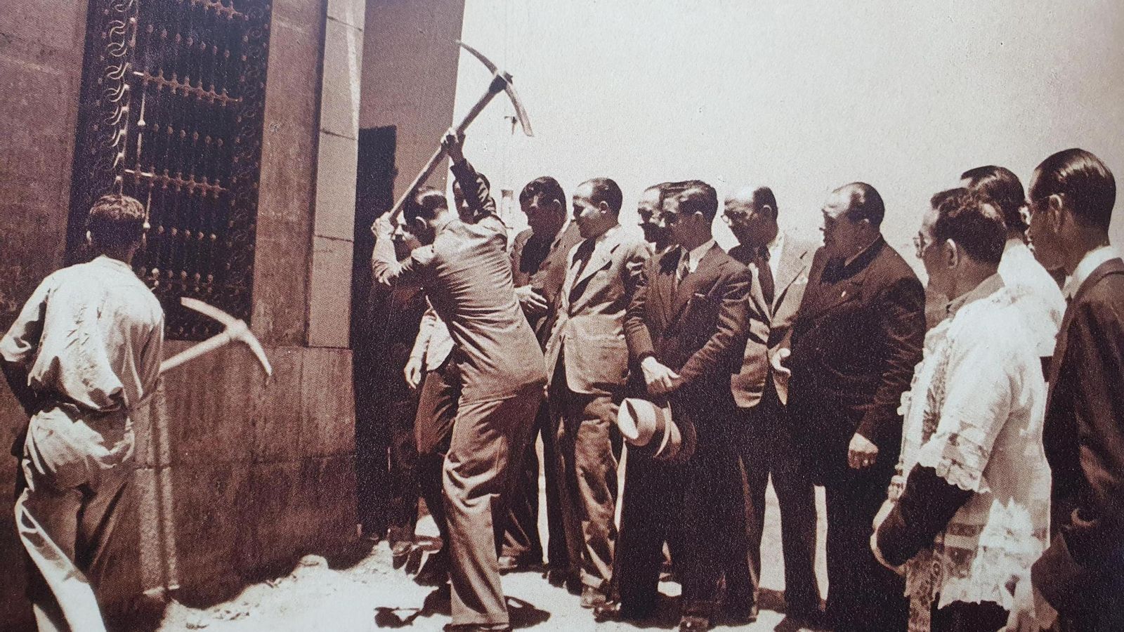 Gallego Burin, piqueta en mano, demuele la primera casa de La Manigua en 1940.