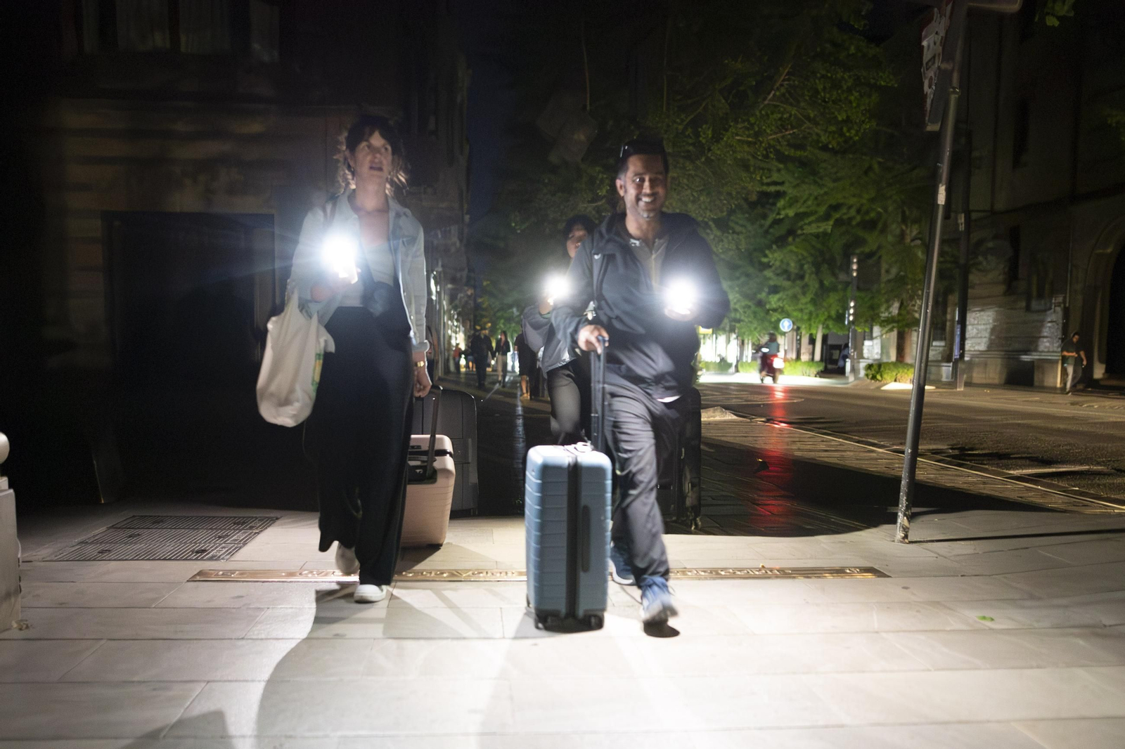 Unos turistas caminan por la Gran Vía con linternas.