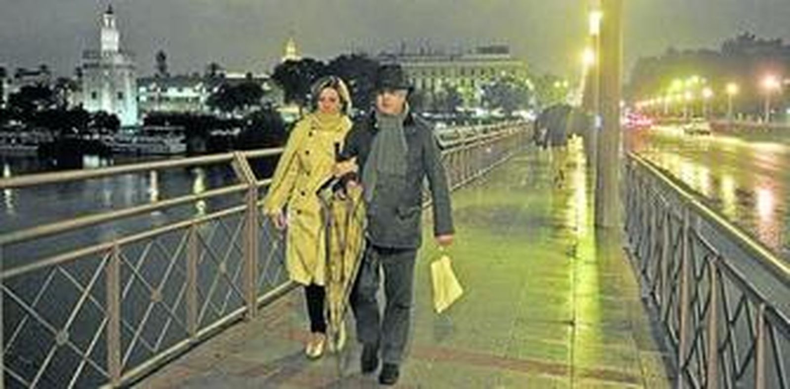El frío ya se hizo notar anoche en Sevilla, en la imagen una pareja pasea por el puente de Los Remedios.