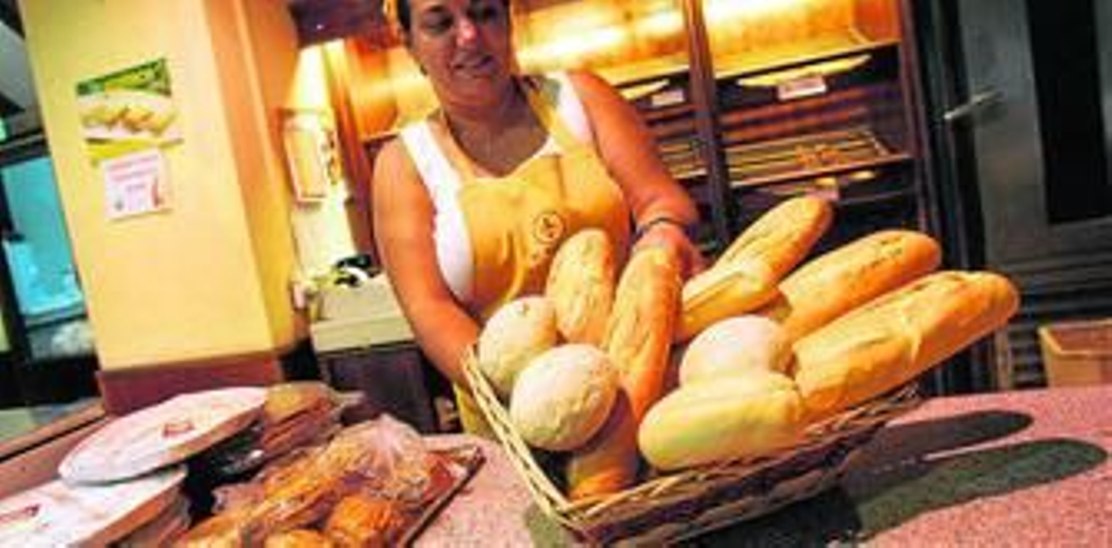 Trabajadora de una panadería muestra las piezas recién horneadas.