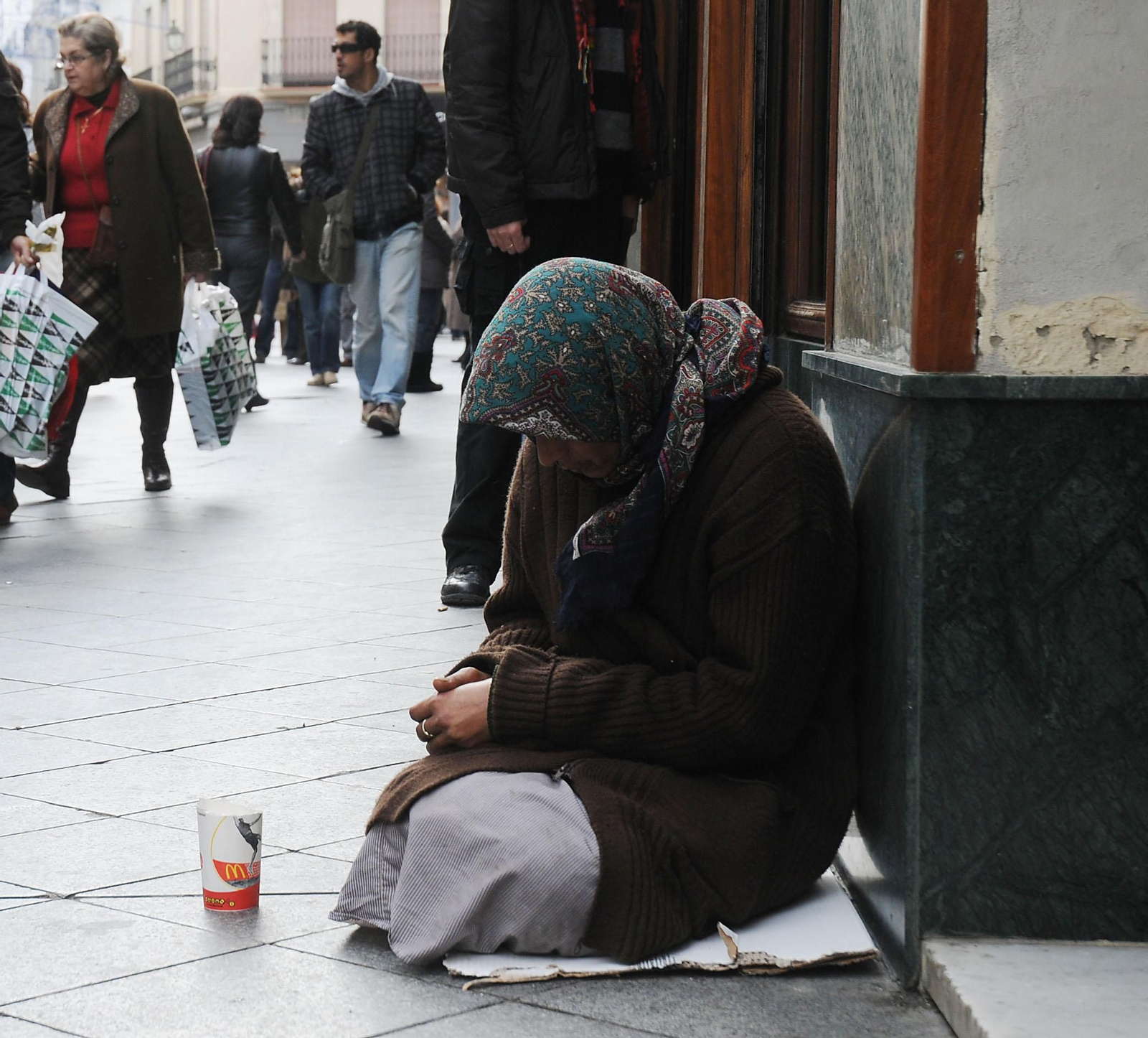 Una persona sin hogar pidiendo en la calle durante el invierno.