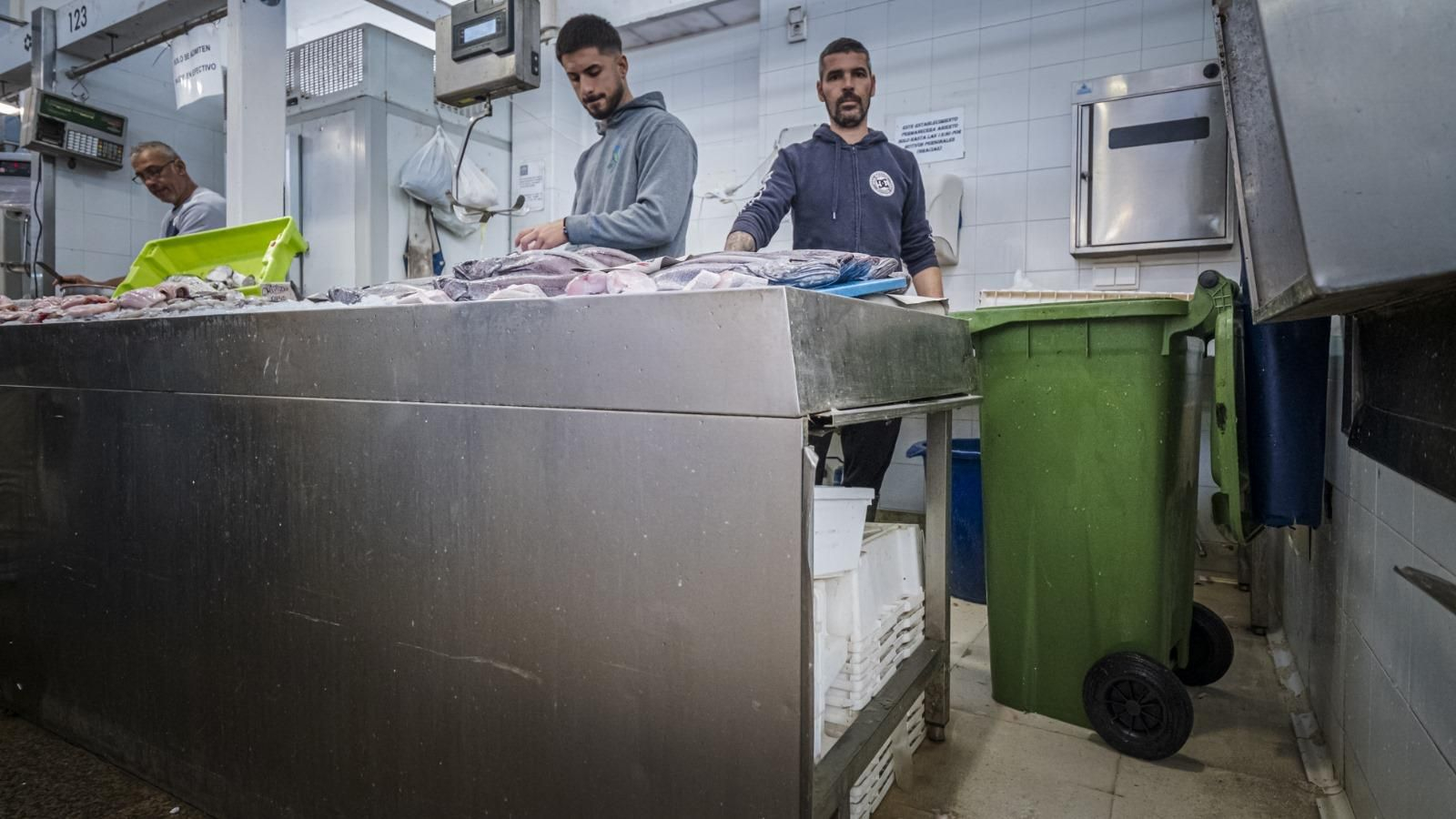 Dos pescaderos del Mercado Central junto a la cubeta verde de Harinas de Andalucía.