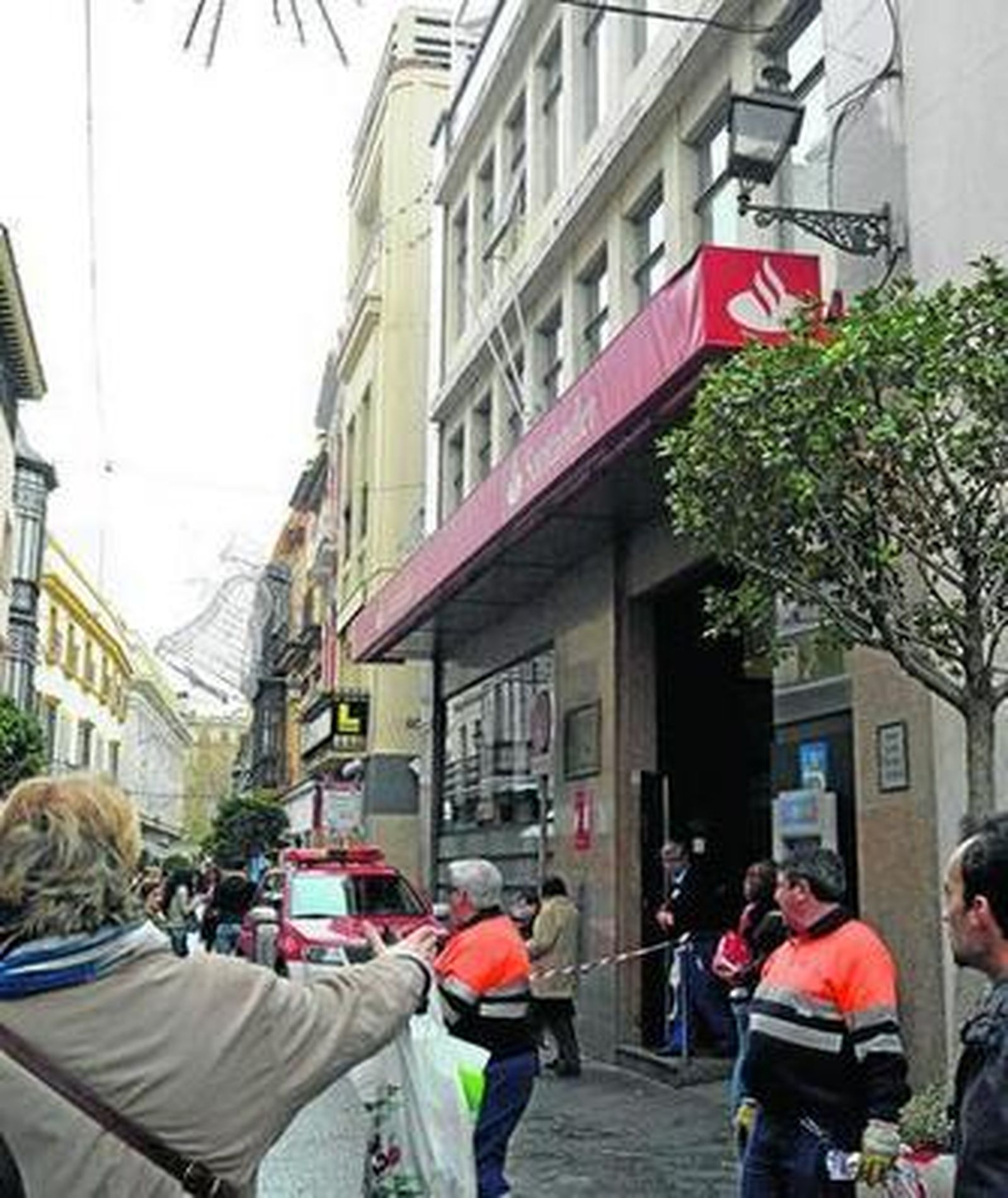 Una mujer señala el lugar del suceso, donde se puede observar el daño en la farola y la cornisa.