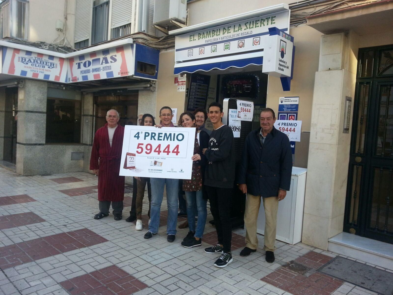 Propietarios de la administración de calle Valle de Abdalajís, en la capital, con el cartel del cuarto premio que han repartido.