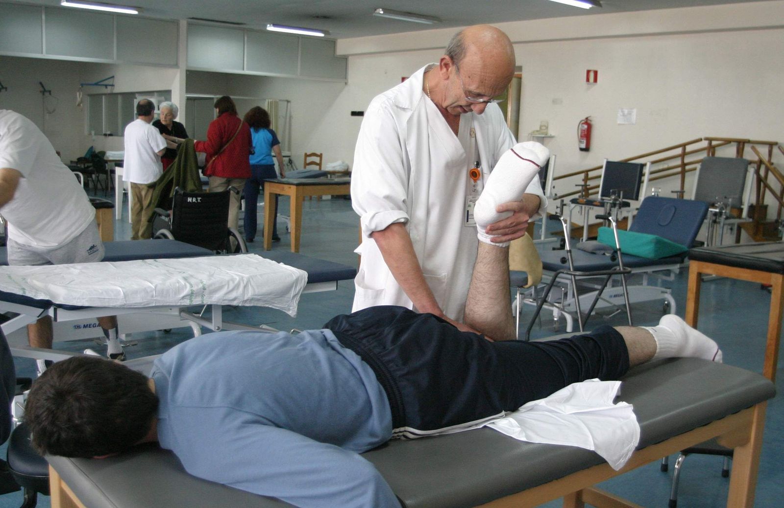 Un fisioterapeuta realiza ejercicios a un paciente.
