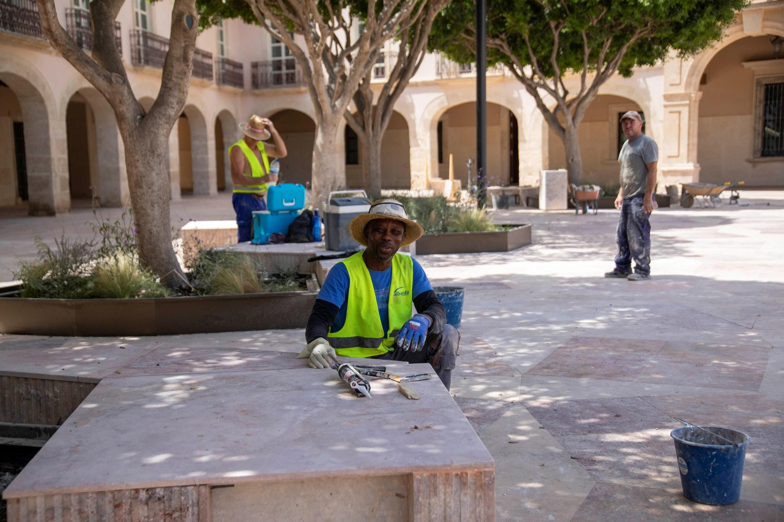 Obreros rehacen los conjuntos de bancos y jardineras repartidos por la plaza.