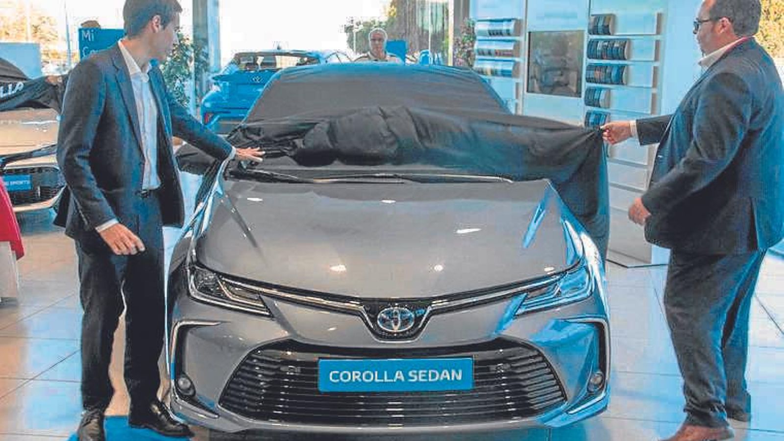 Dos comerciales levantan la lona que cubría el Toyota Corolla Sedan durante la presentación.