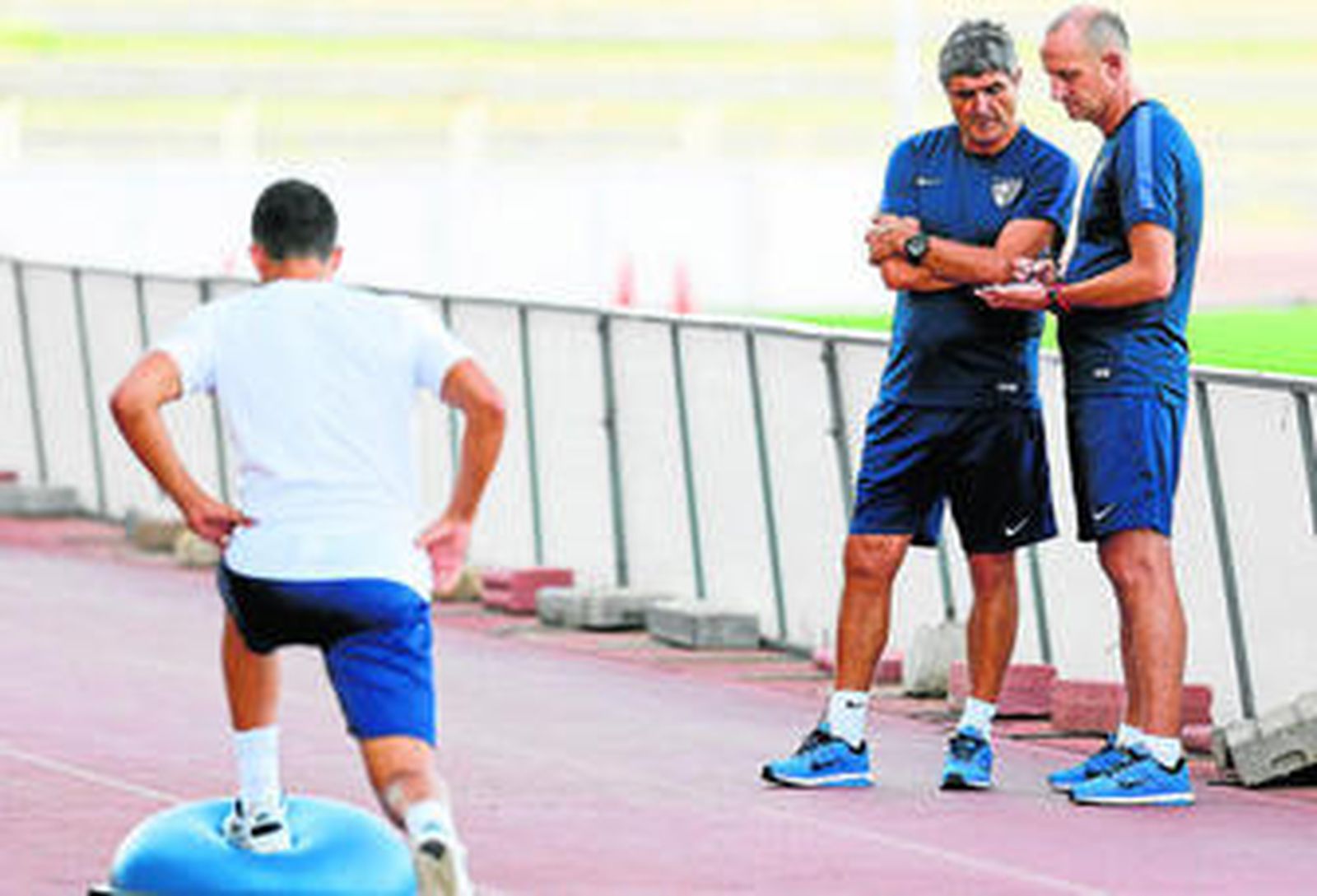 Juande observa las indicaciones de su segundo, José Gómez, en presencia de un jugador del Málaga.